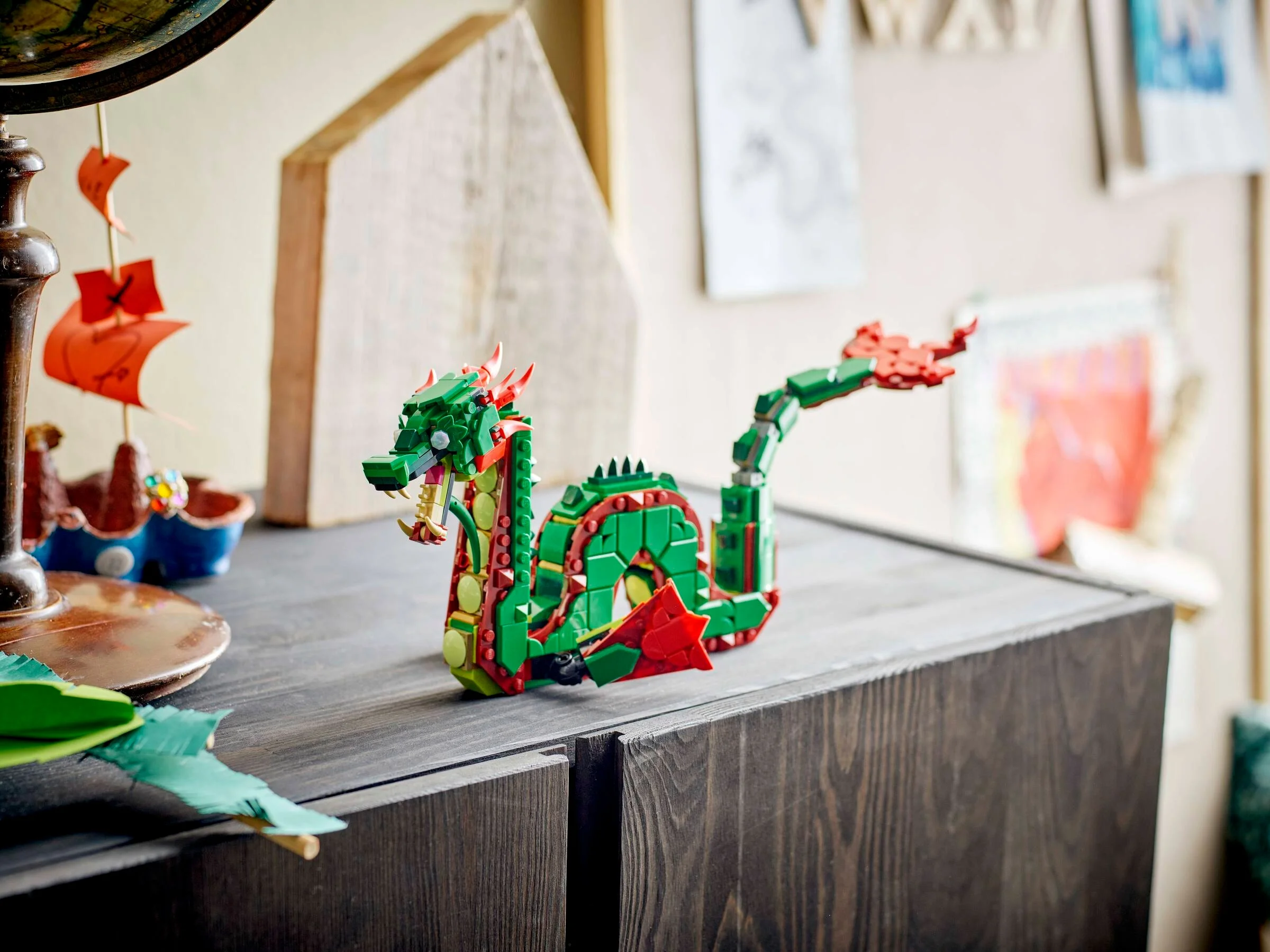 Dragonul medieval LEGO Creator 31161, verde și roșu, stând pe o comodă. Detaliile modelului sunt vizibile.