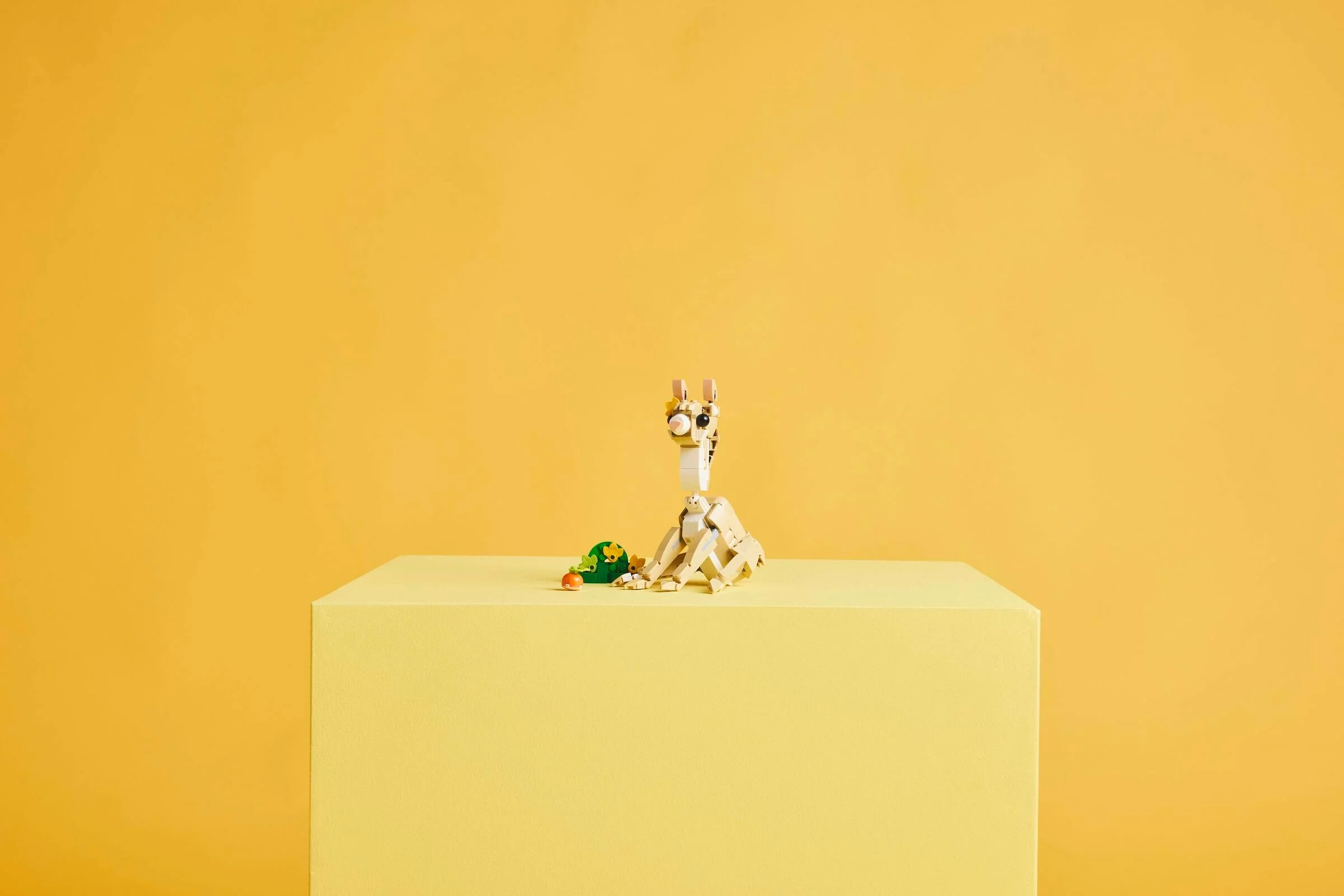 Imagine cu iepurașul LEGO Creator 31162, așezat lângă o frunză și o morcov pe un cub galben.