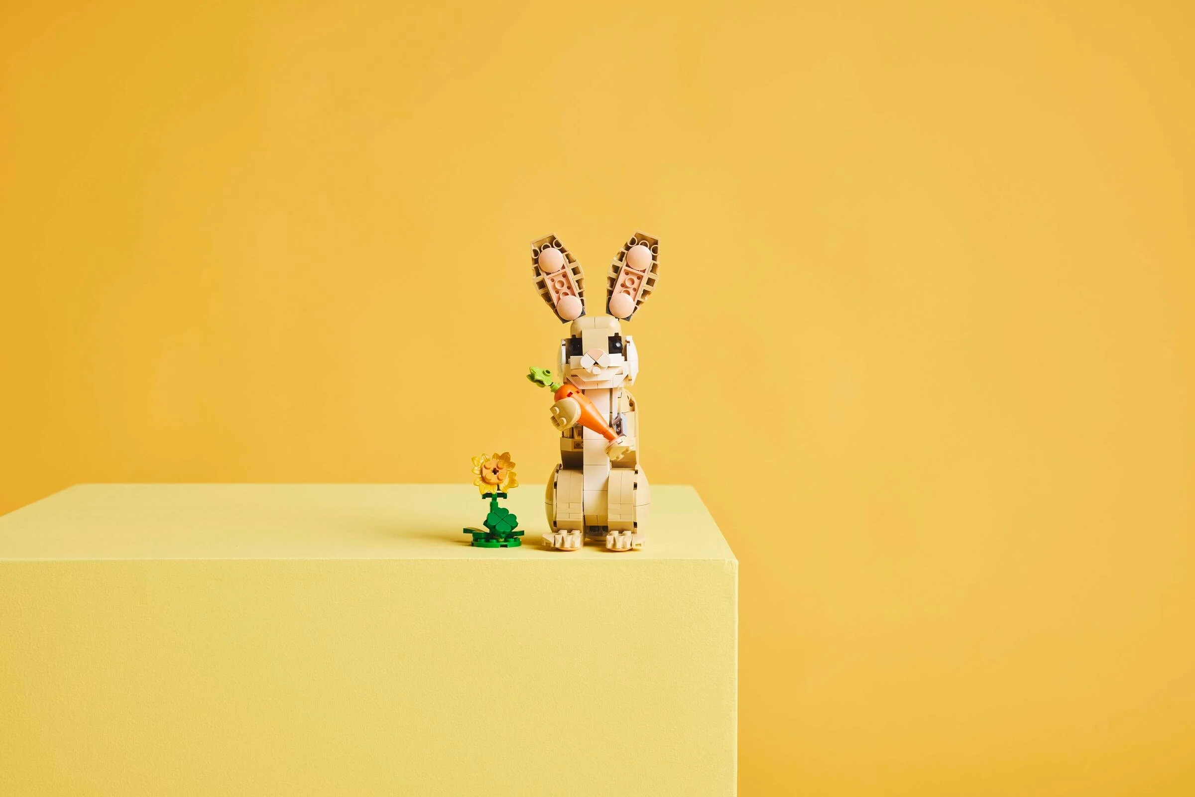 Imagine cu iepurașul LEGO Creator 31162 și o floare, pe fundal galben.