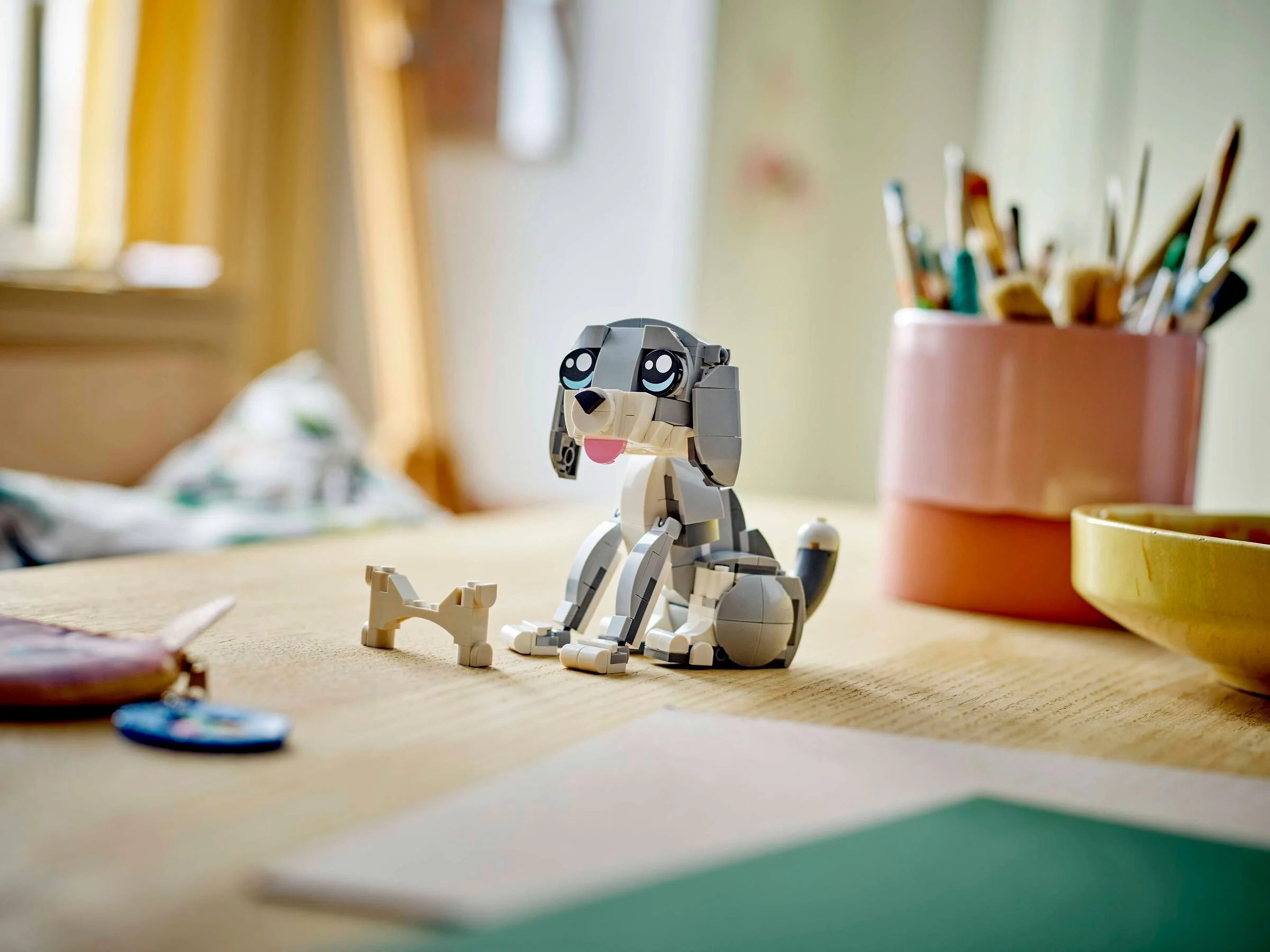 Pisica jucăușă LEGO Creator, șezând, cu os. Un cadru luminos și prietenos.
