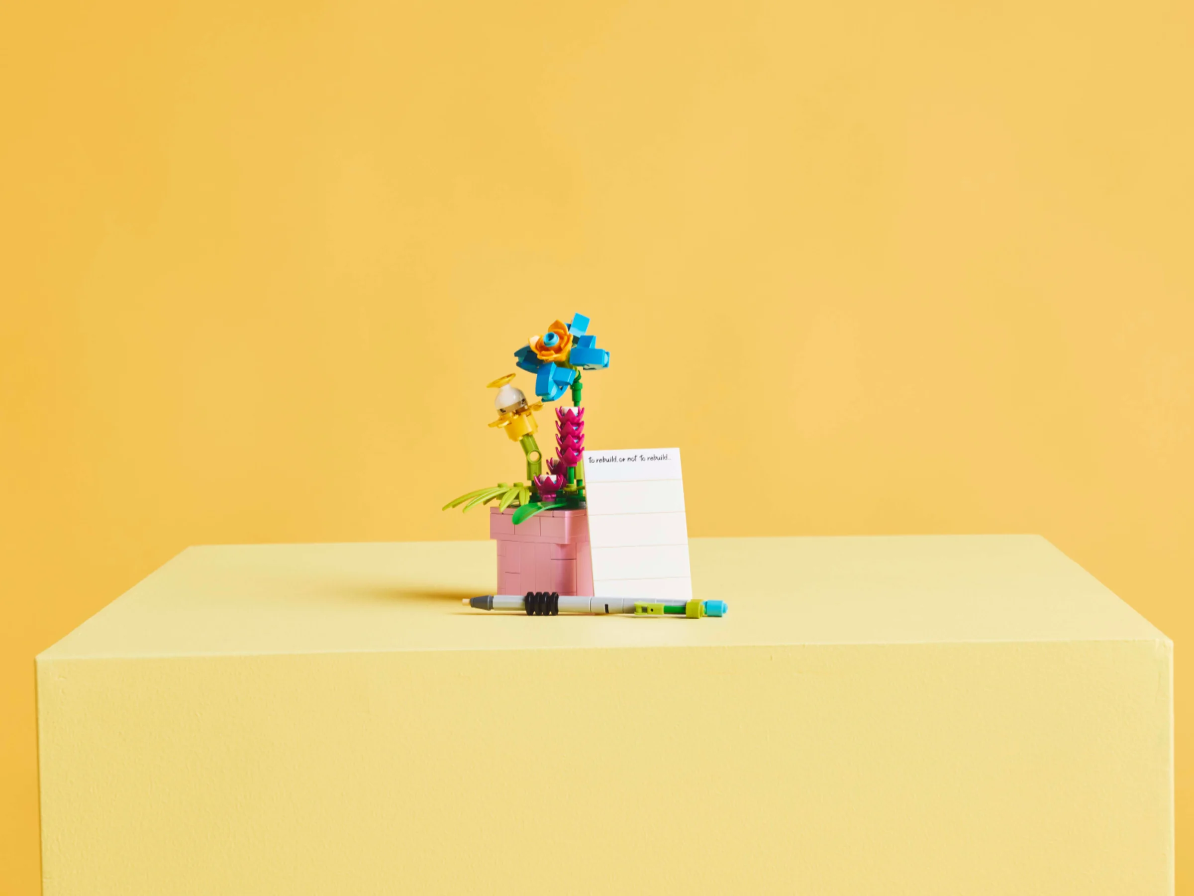 Imagine cu setul LEGO 31169, cu flori construite și o notă, pe un fundal galben.