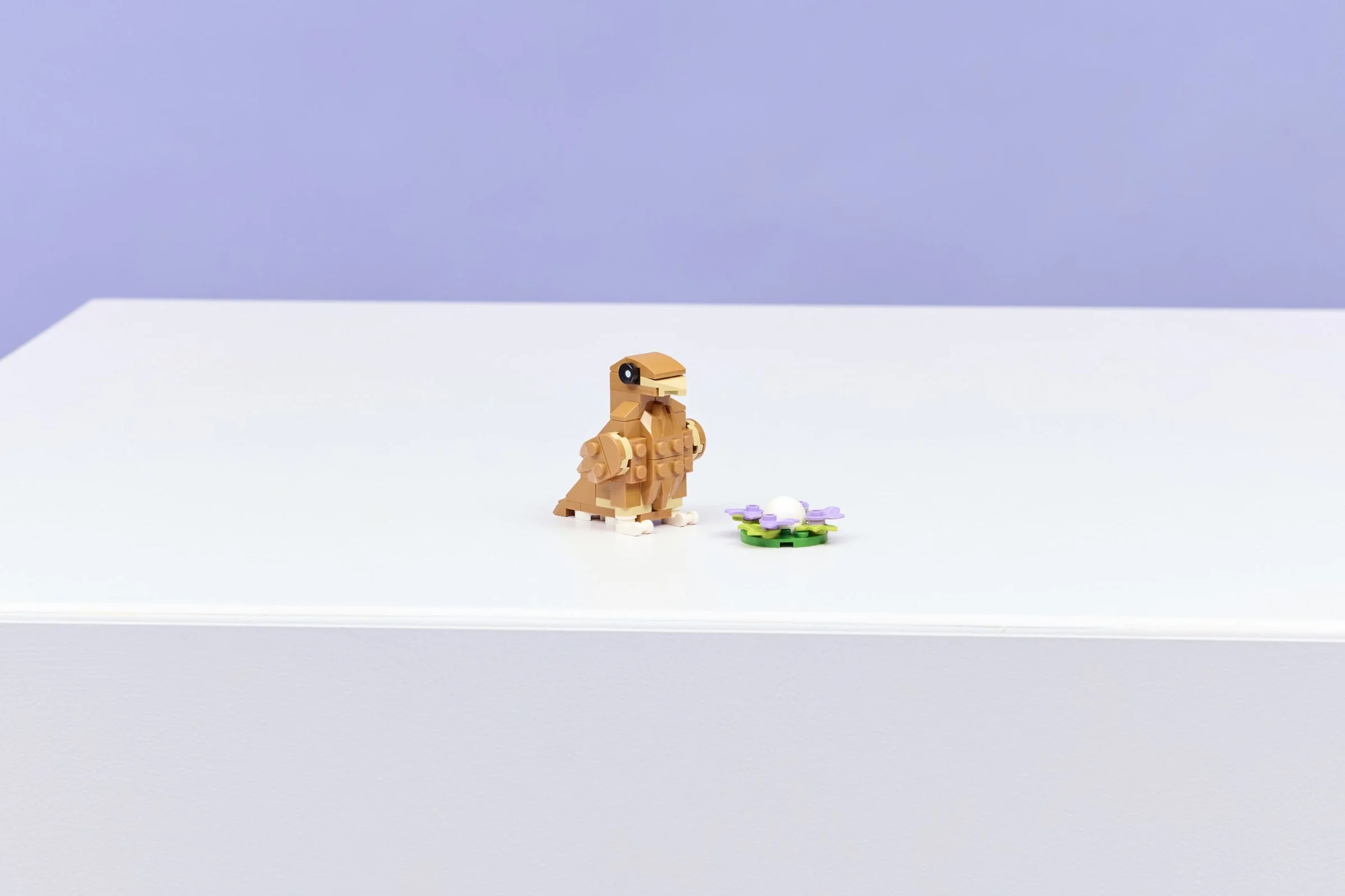 Un hamster drăguț LEGO lângă o floare cu un element alb rotund în centru.