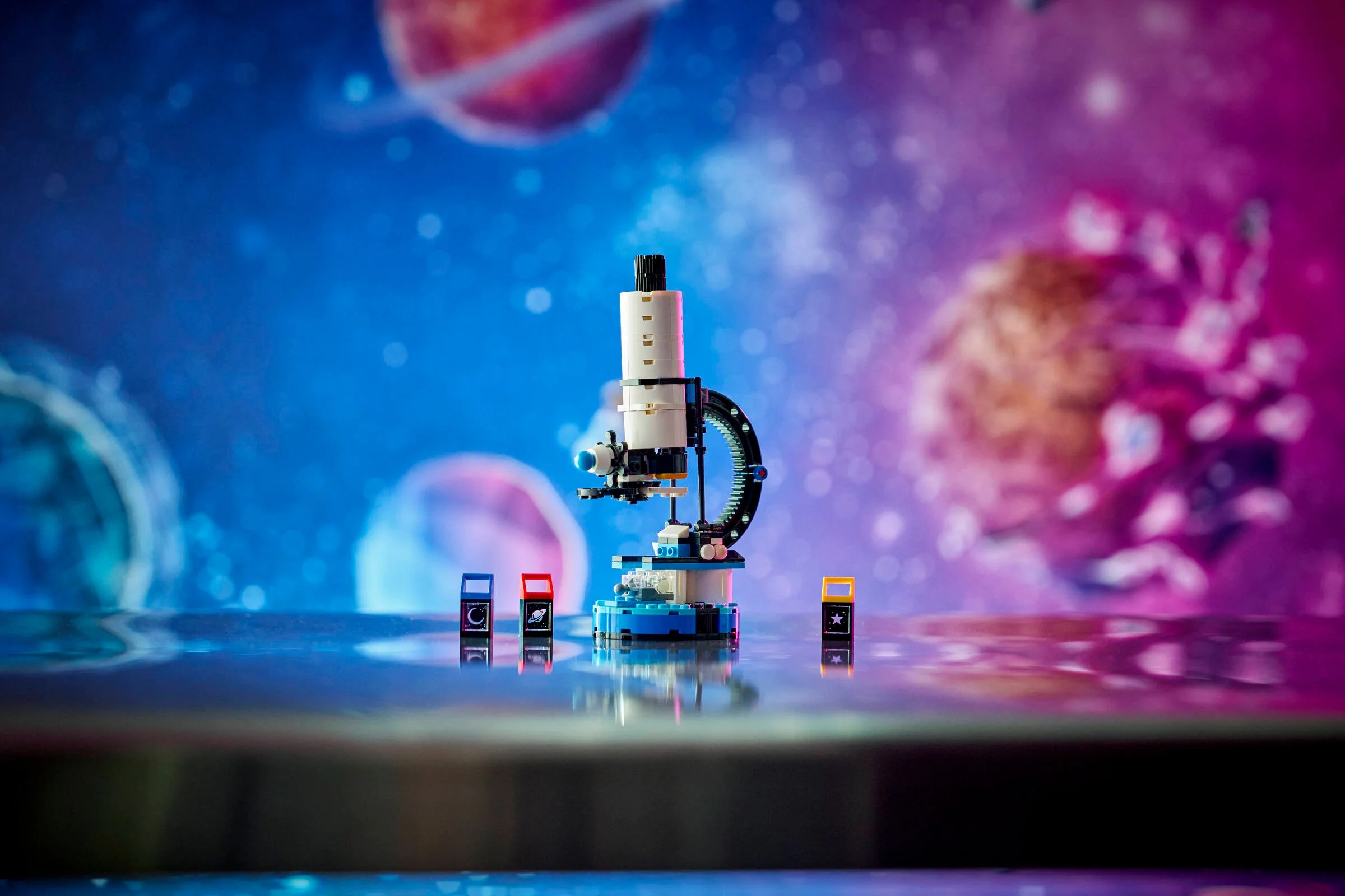 Telescopul spațial LEGO Creator, un model albastru și alb pe un fundal cosmic colorat.