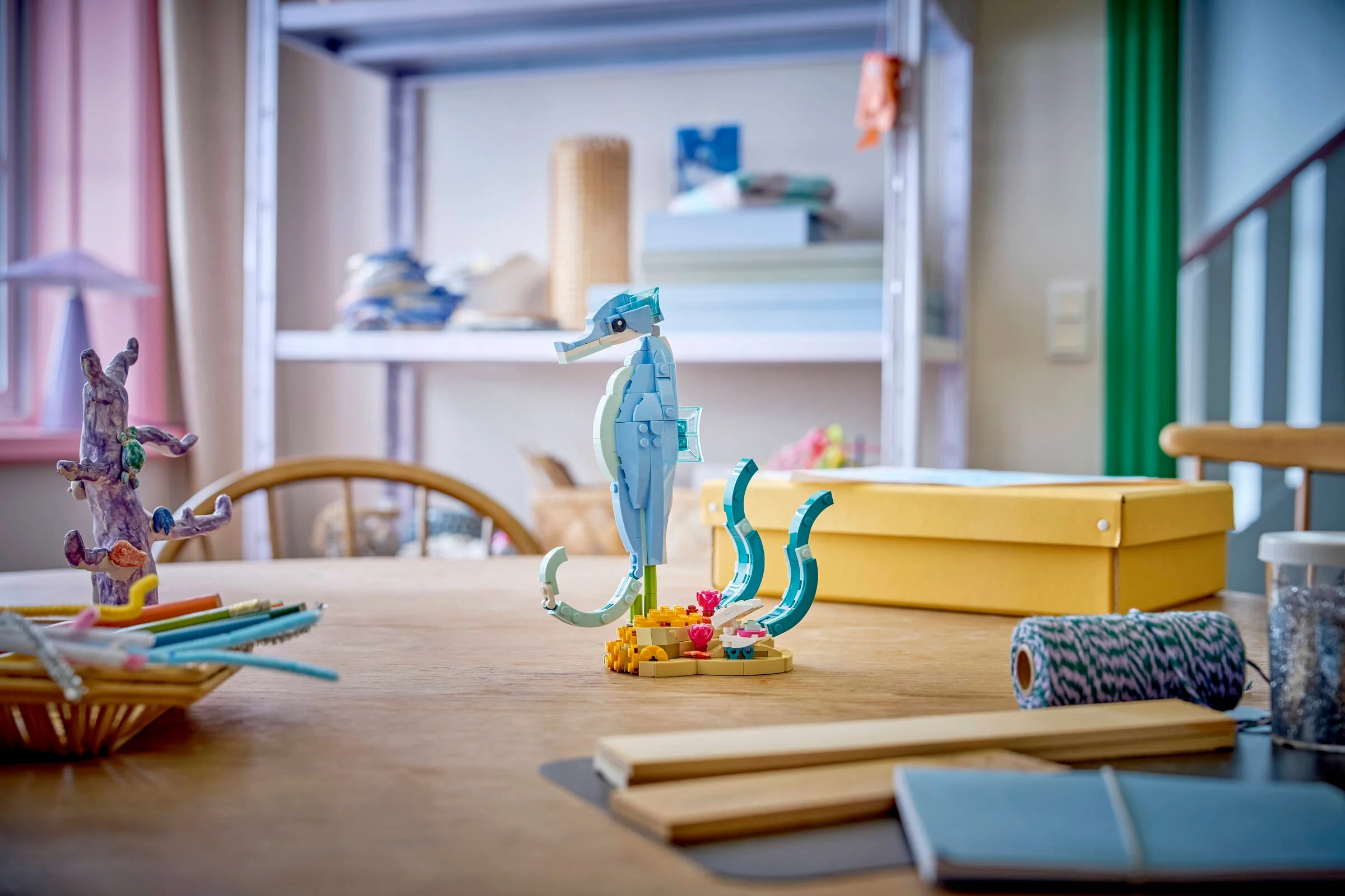 Un seahorse LEGO albastru, înconjurat de elemente decorative pe o masă. Model Creator detaliat.