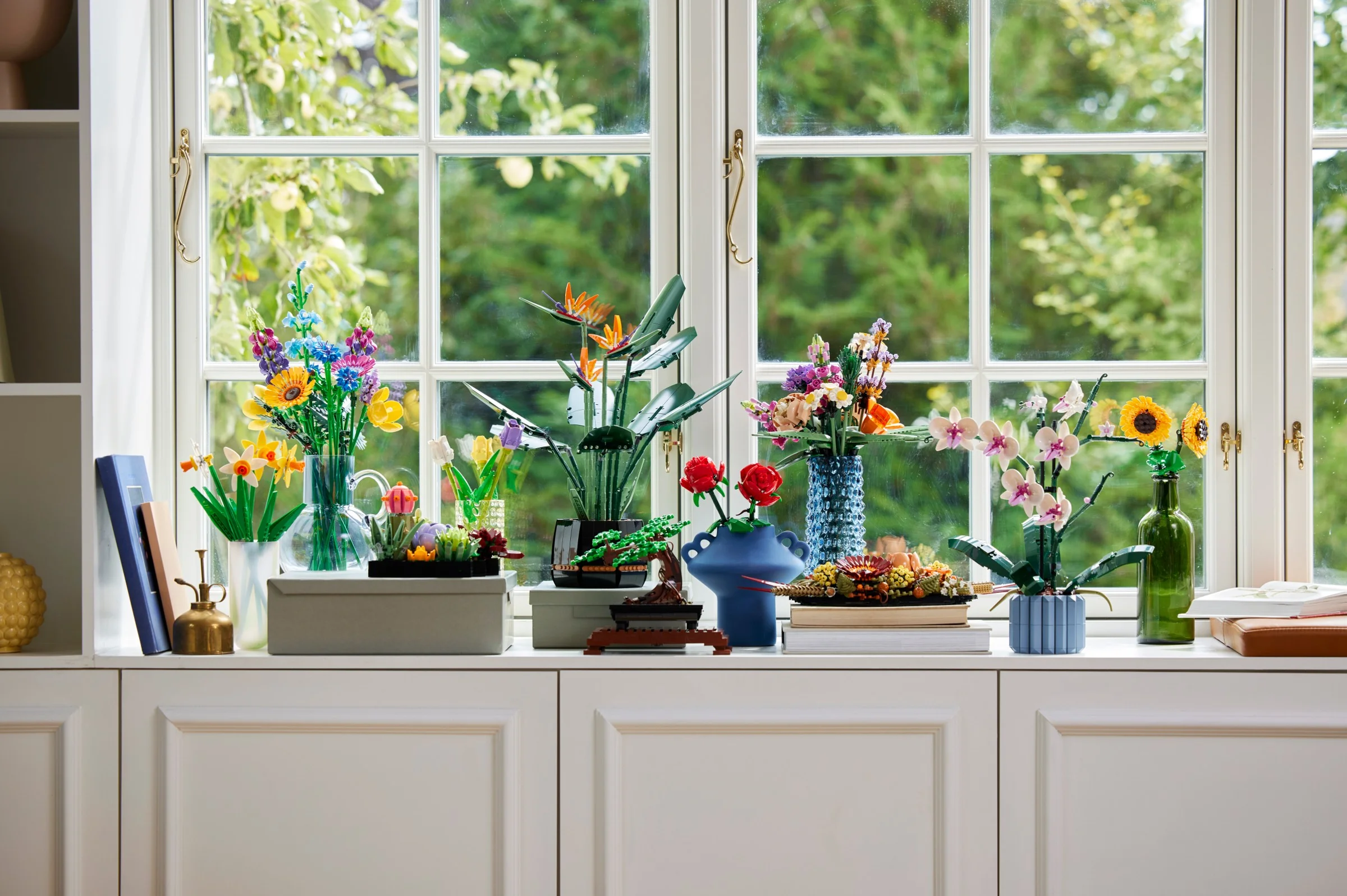 Diverse seturi LEGO Botanicals, inclusiv 40524, expuse pe un pervaz luminos.