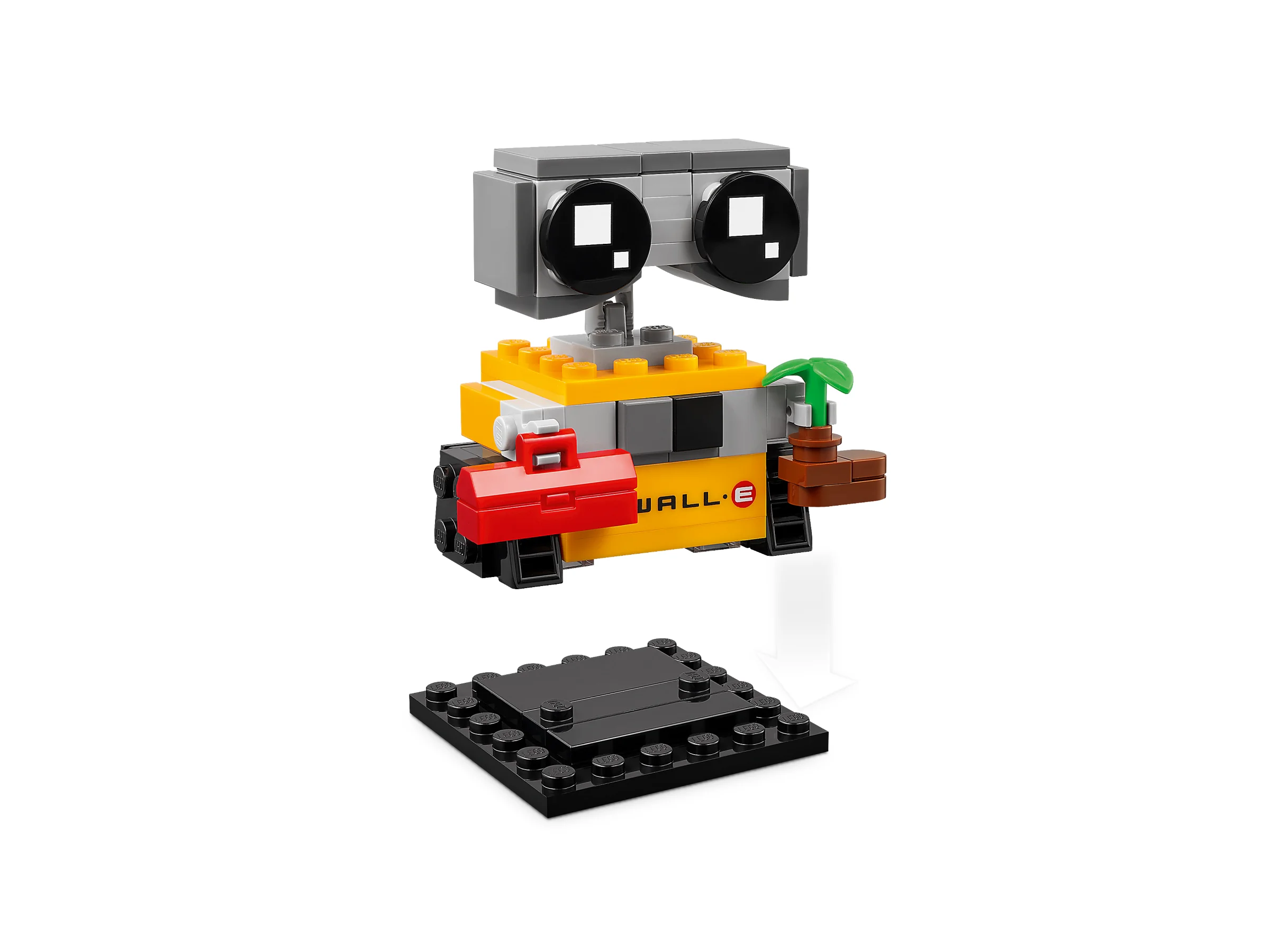 WALL-E BrickHeadz, galben, cu o plantă și cutie de scule roșie, stând lângă o placă neagră.