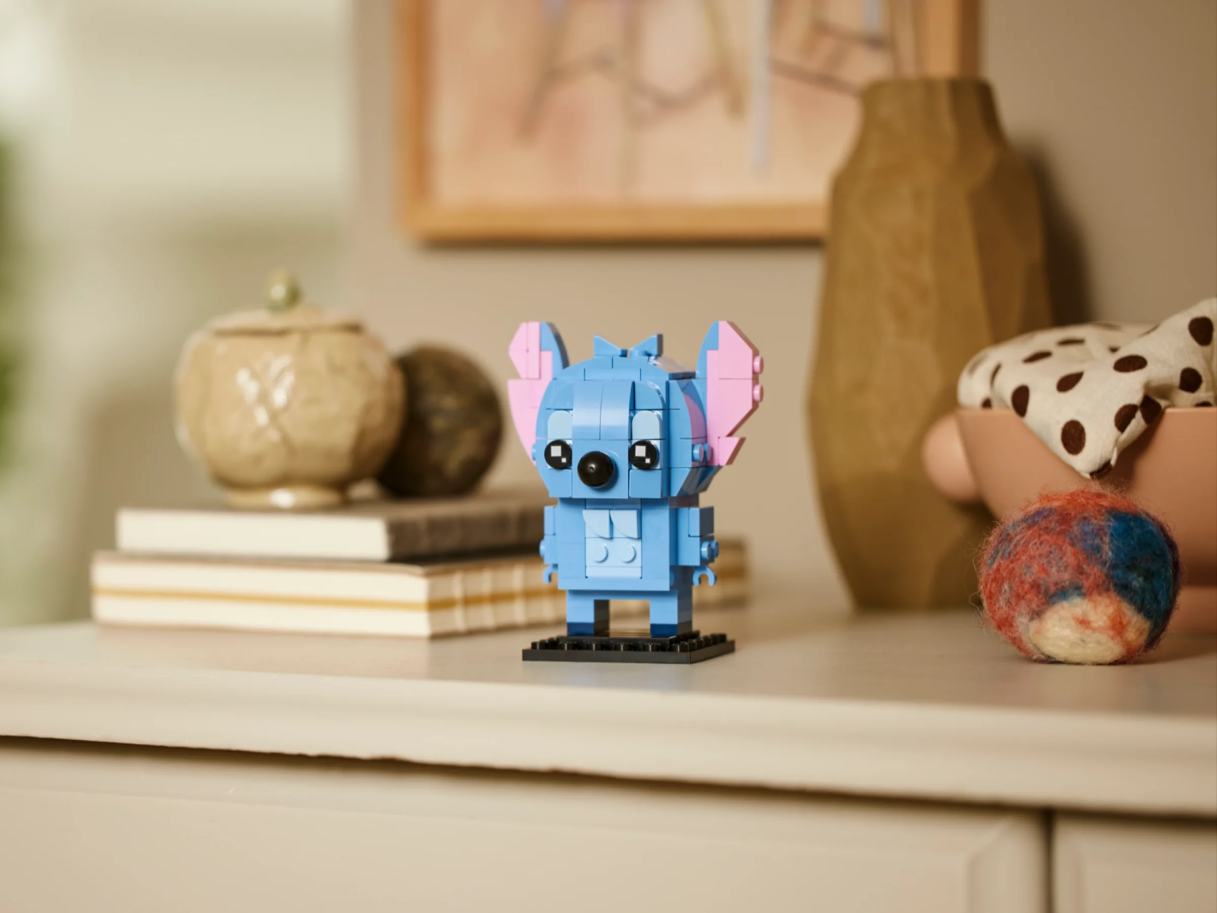 Prim plan cu Stitch BrickHeadz, drăguț și albastru, pe o suprafață bej. Figurina e detaliată și atractivă.