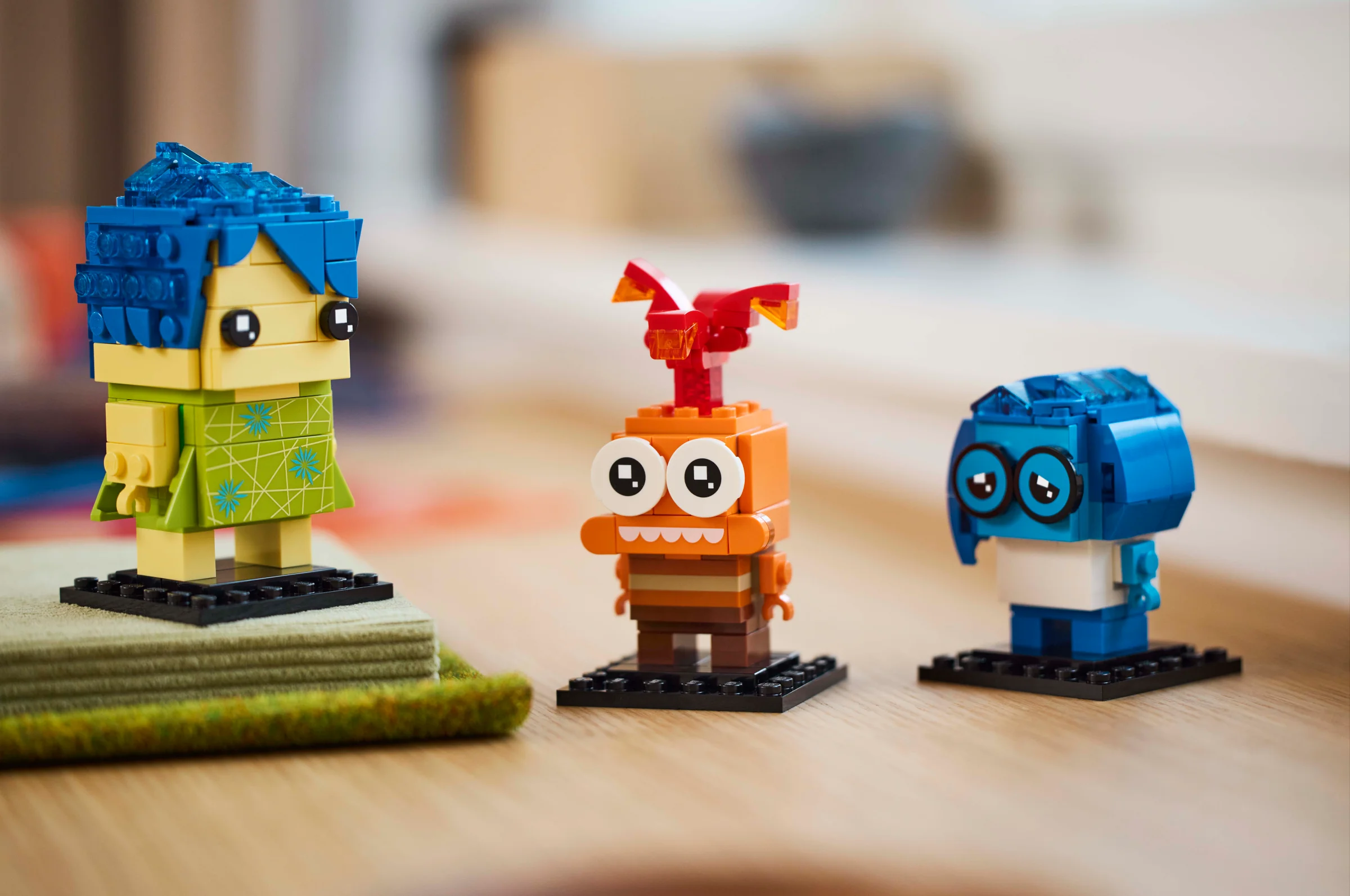 Imagine cu cele trei figurine BrickHeadz: Bucurie, Tristețe și Anxietate. Sunt viu colorate.