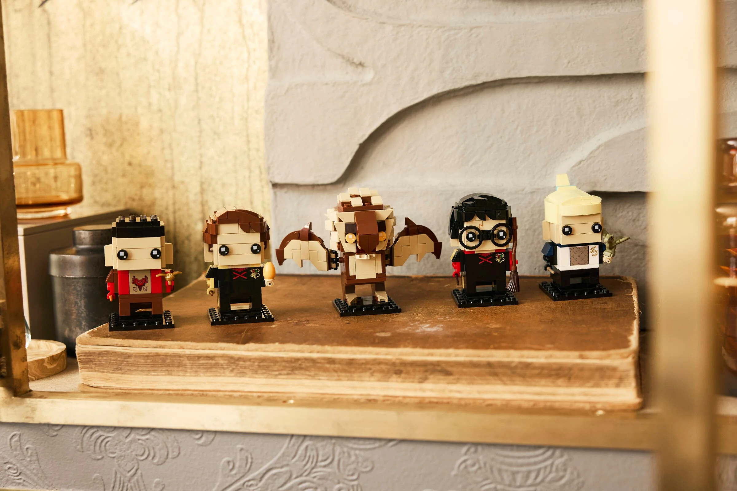 Imagine cu figurinele BrickHeadz din setul LEGO 40791 Goblet of Fire, aranjate pe o carte.