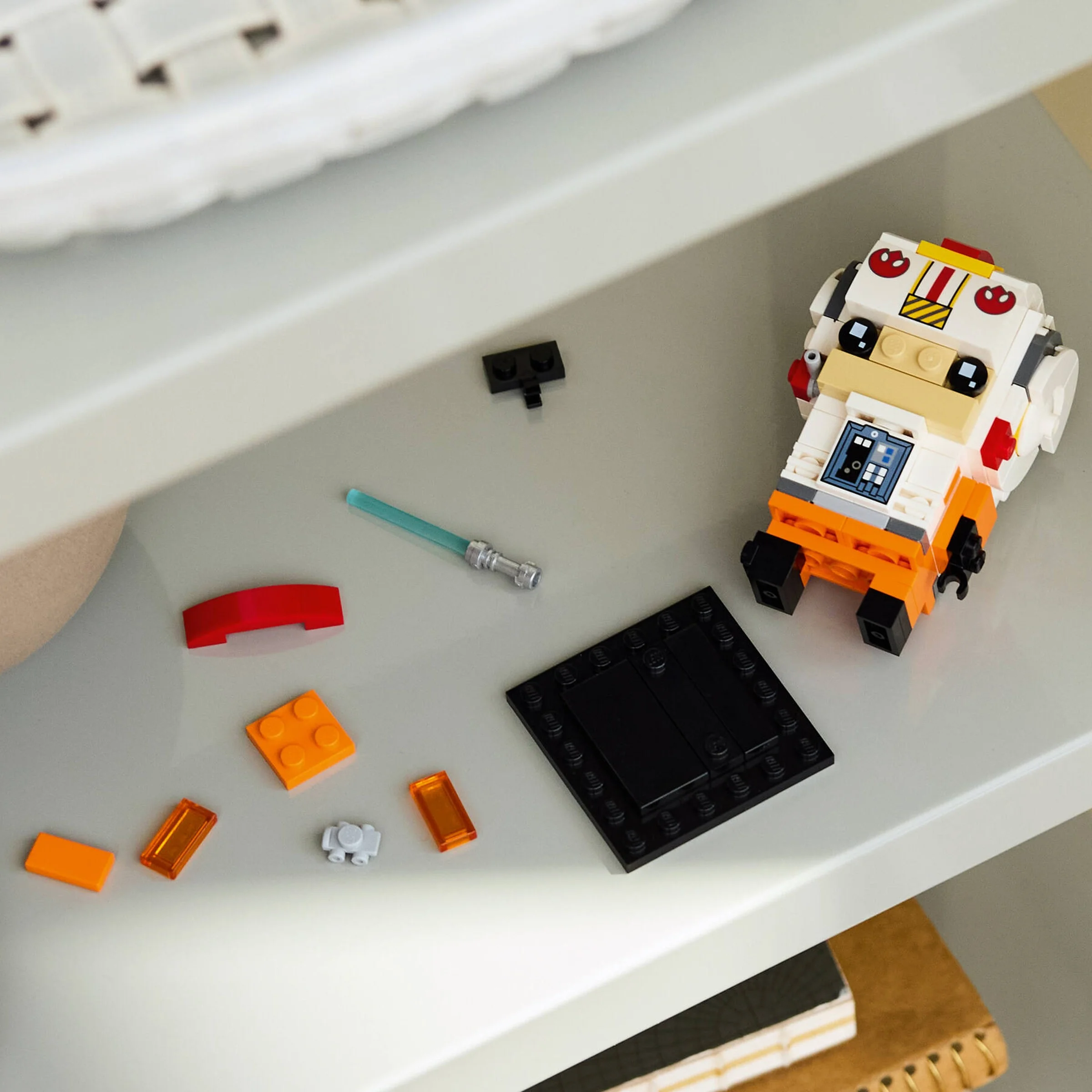 O imagine a setului LEGO BrickHeadz Luke Skywalker pilot rebel, parțial asamblat pe o poliță albă.