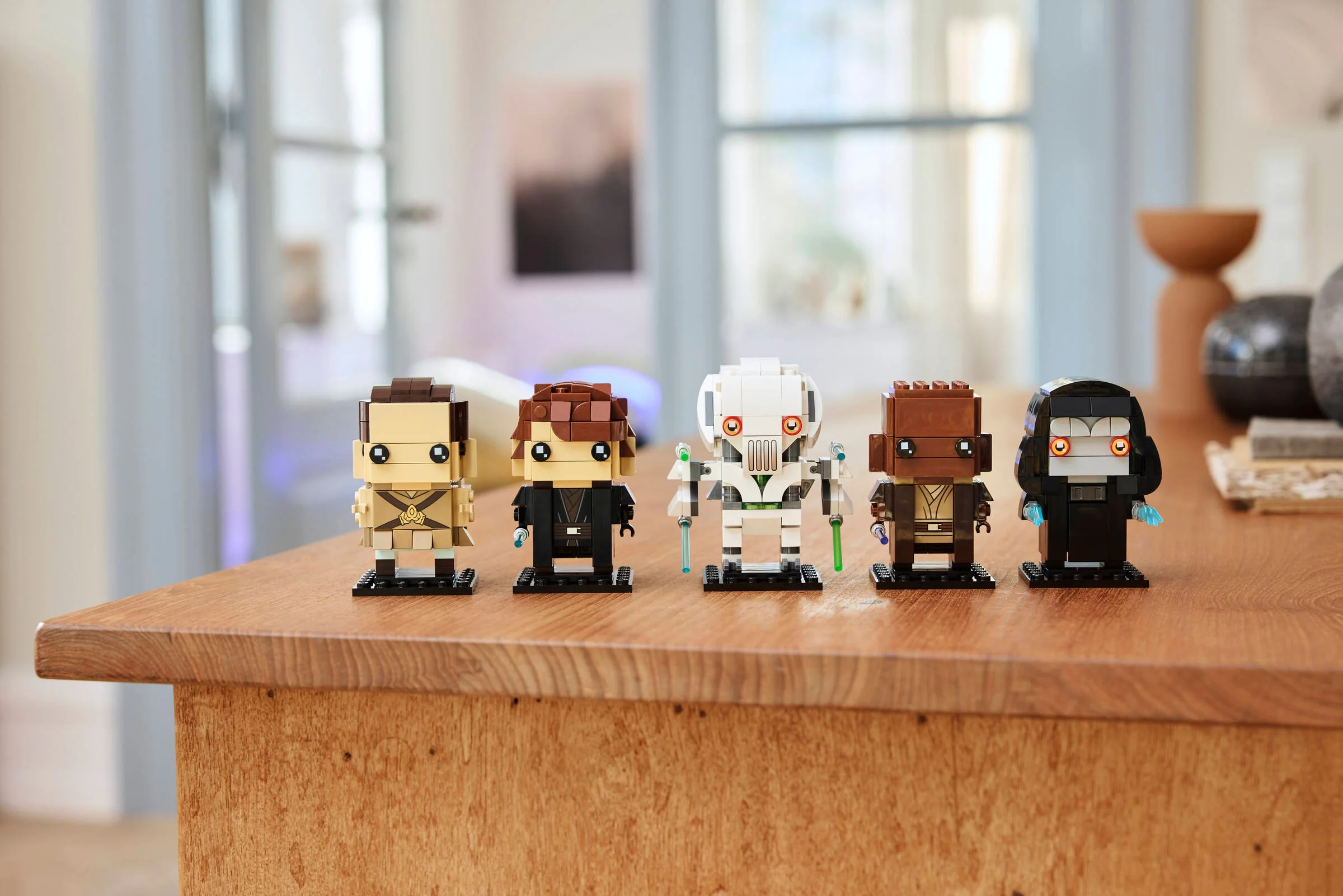 Setul LEGO BrickHeadz 40796 prezintă 5 personaje din Răzbunarea Sith, pe un blat de lemn.