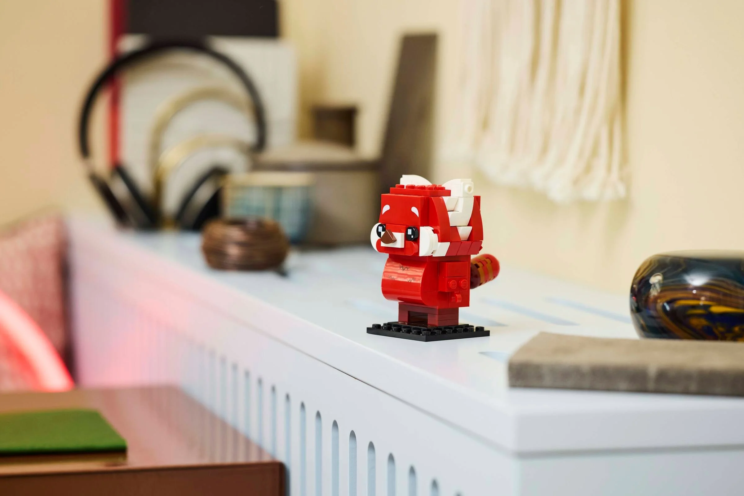 Imagine cu setul LEGO BrickHeadz 40798, Panda Roșu Mei, prezentat pe o poliță, într-un cadru casnic.