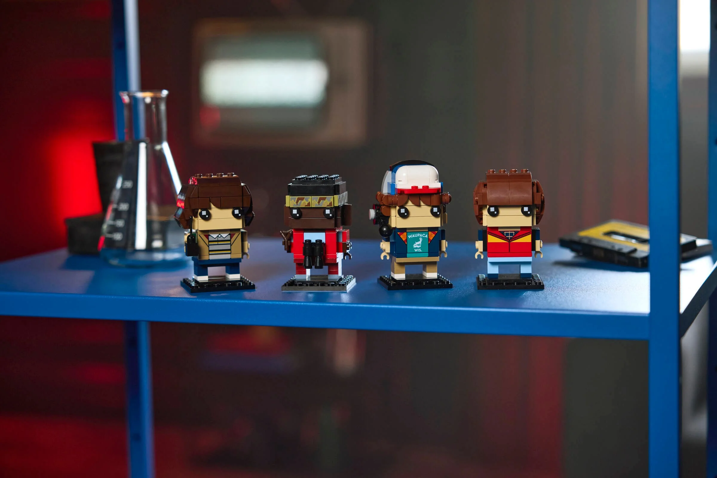 Imagine cu cele patru figurine BrickHeadz Mike, Dustin, Lucas și Will, pe un raft albastru.