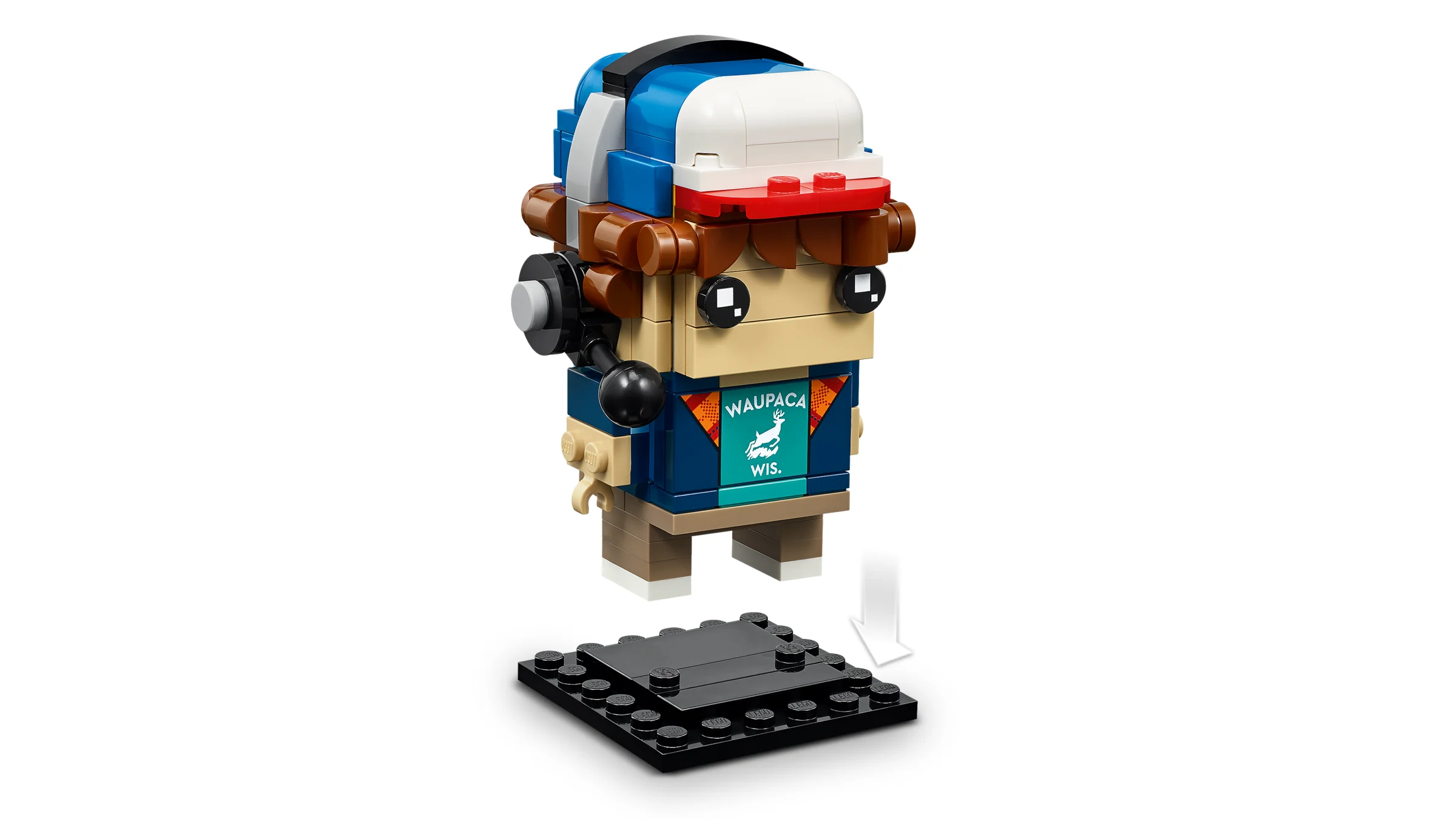 Figurină BrickHeadz Lucas, cu șapcă și tricou inscripționat, poziționată deasupra suportului negru.