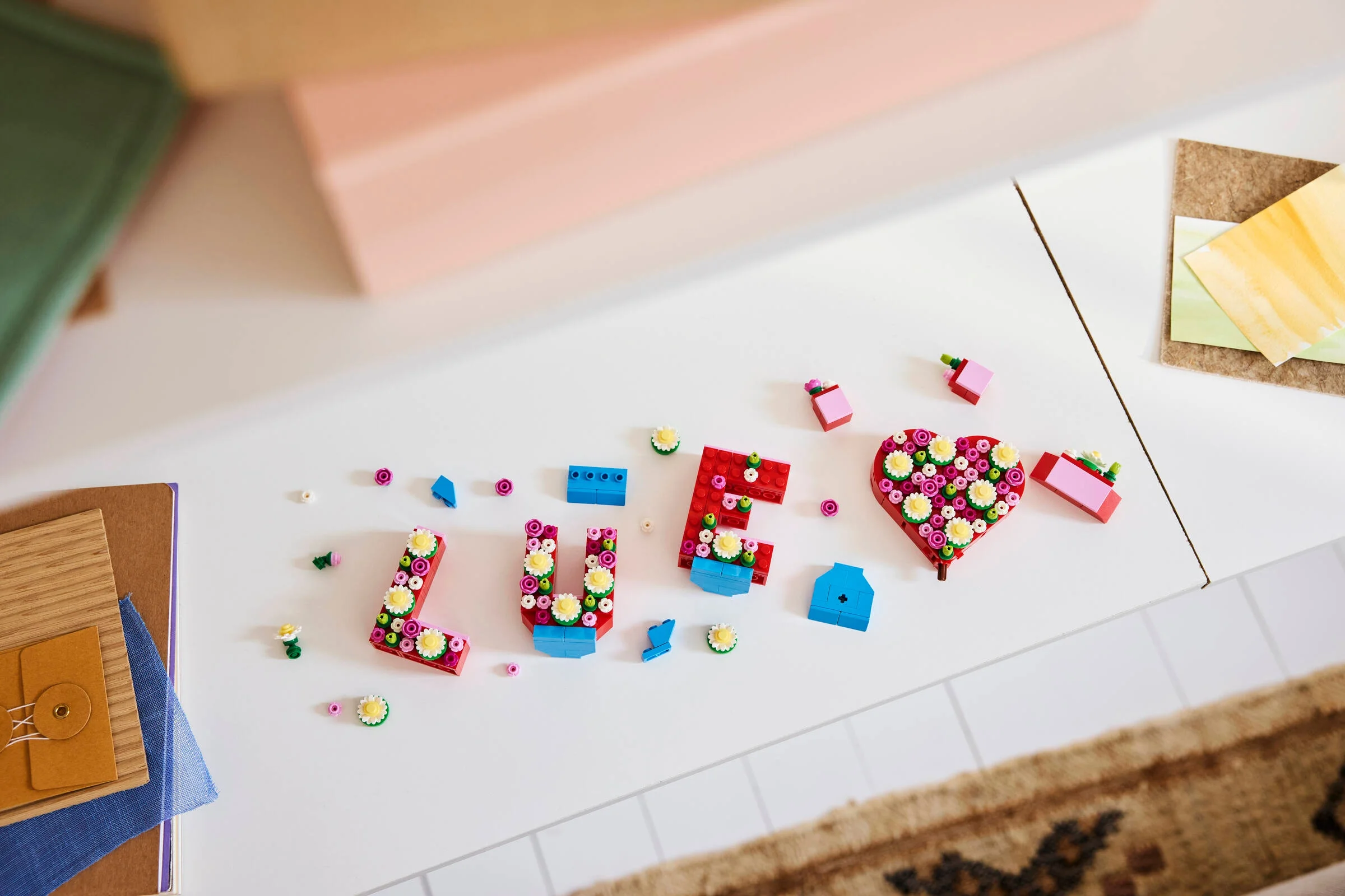 Prezentare detaliată a setului LEGO „Love Letters” (40867), cu litere și o inimă decorate cu flori.