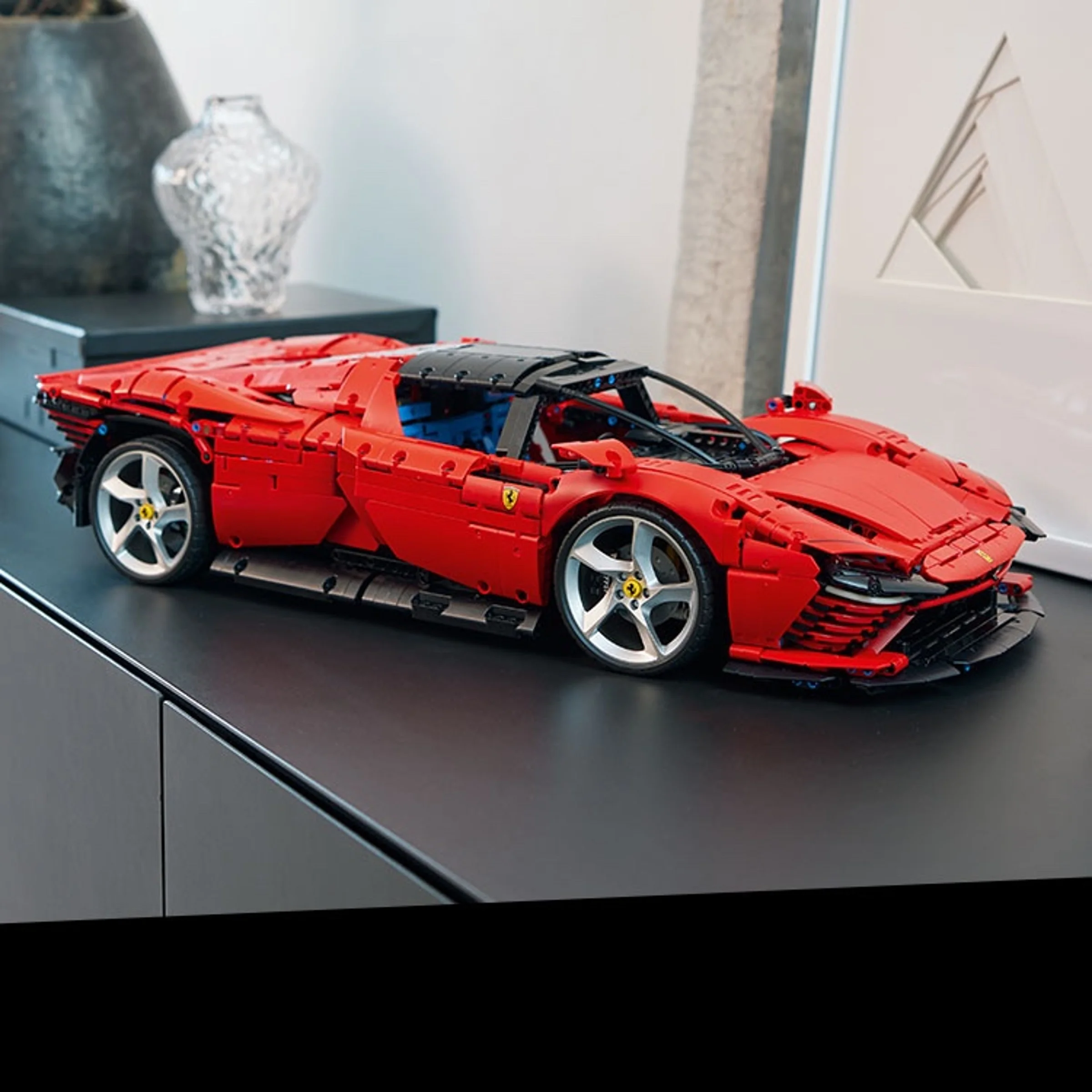 Ferrari Daytona SP3 roșu, model LEGO Technic 42143, expus elegant pe un dulap negru.