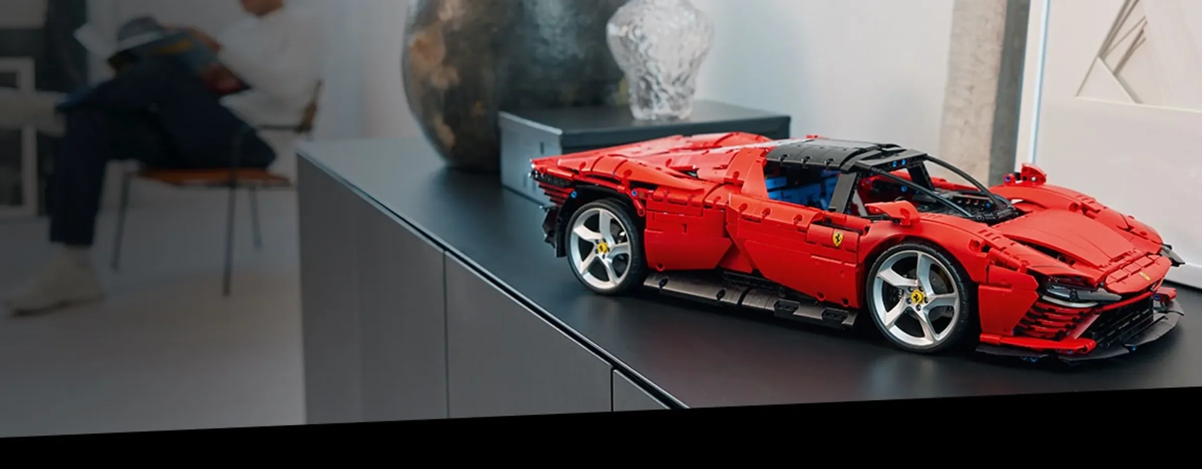 Ferrari Daytona SP3 LEGO Technic roșu, expusă pe un dulap modern. O imagine atractivă.