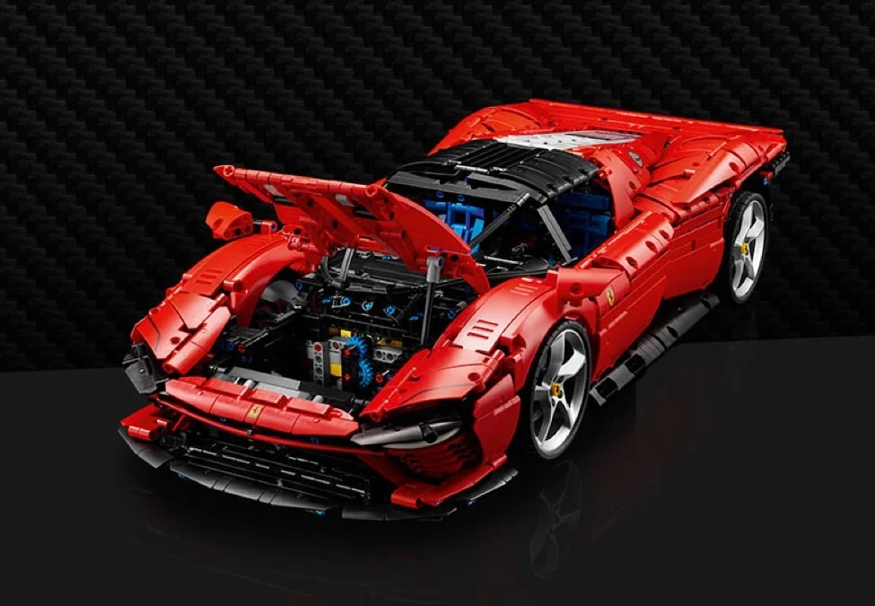 Modelul Ferrari Daytona SP3, roșu, cu capota ridicată, expunând detaliile motorului.