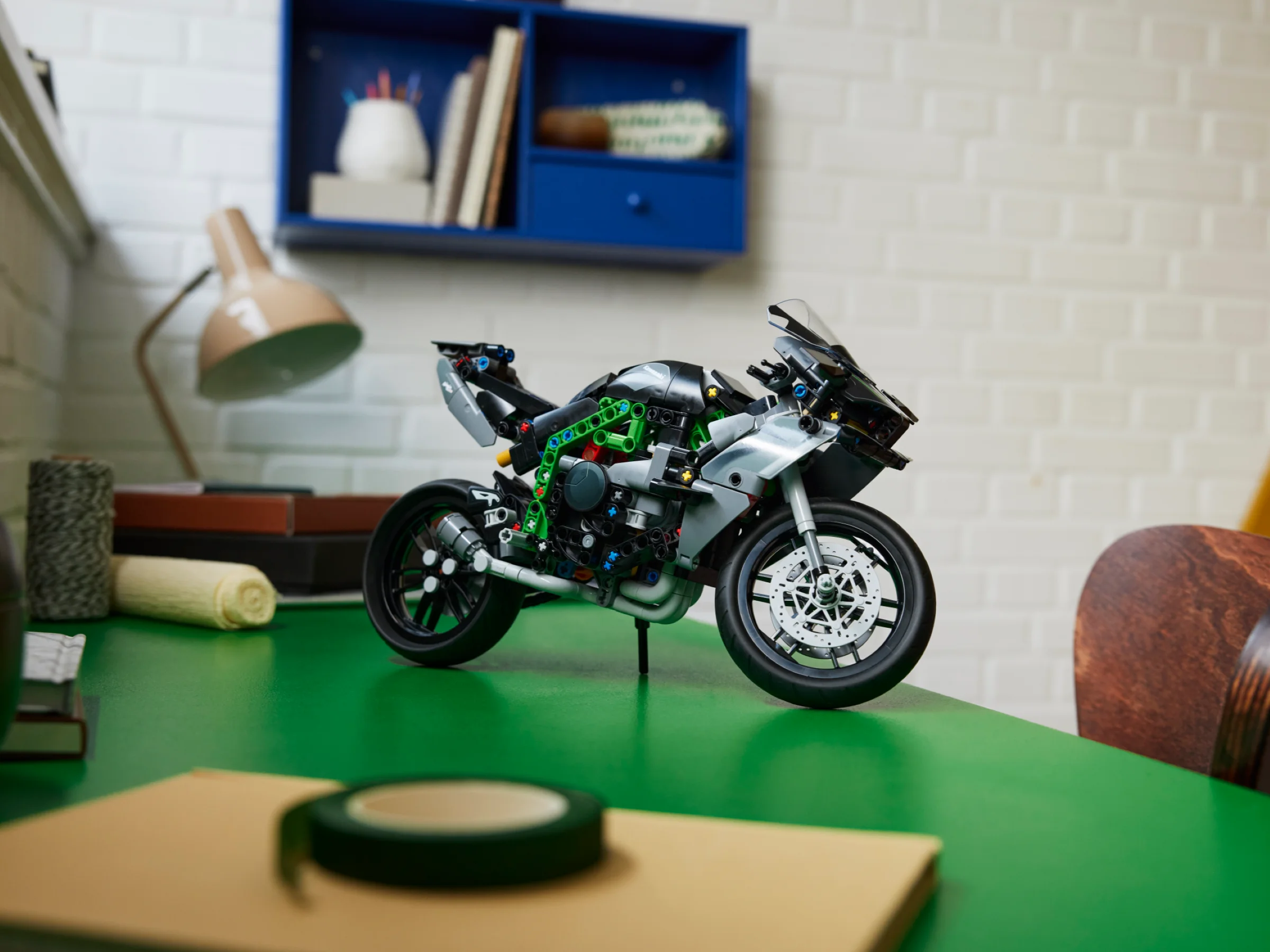 Motocicleta Kawasaki Ninja H2R, modelul LEGO Technic, expusă pe un birou verde, într-o scenă de interior.