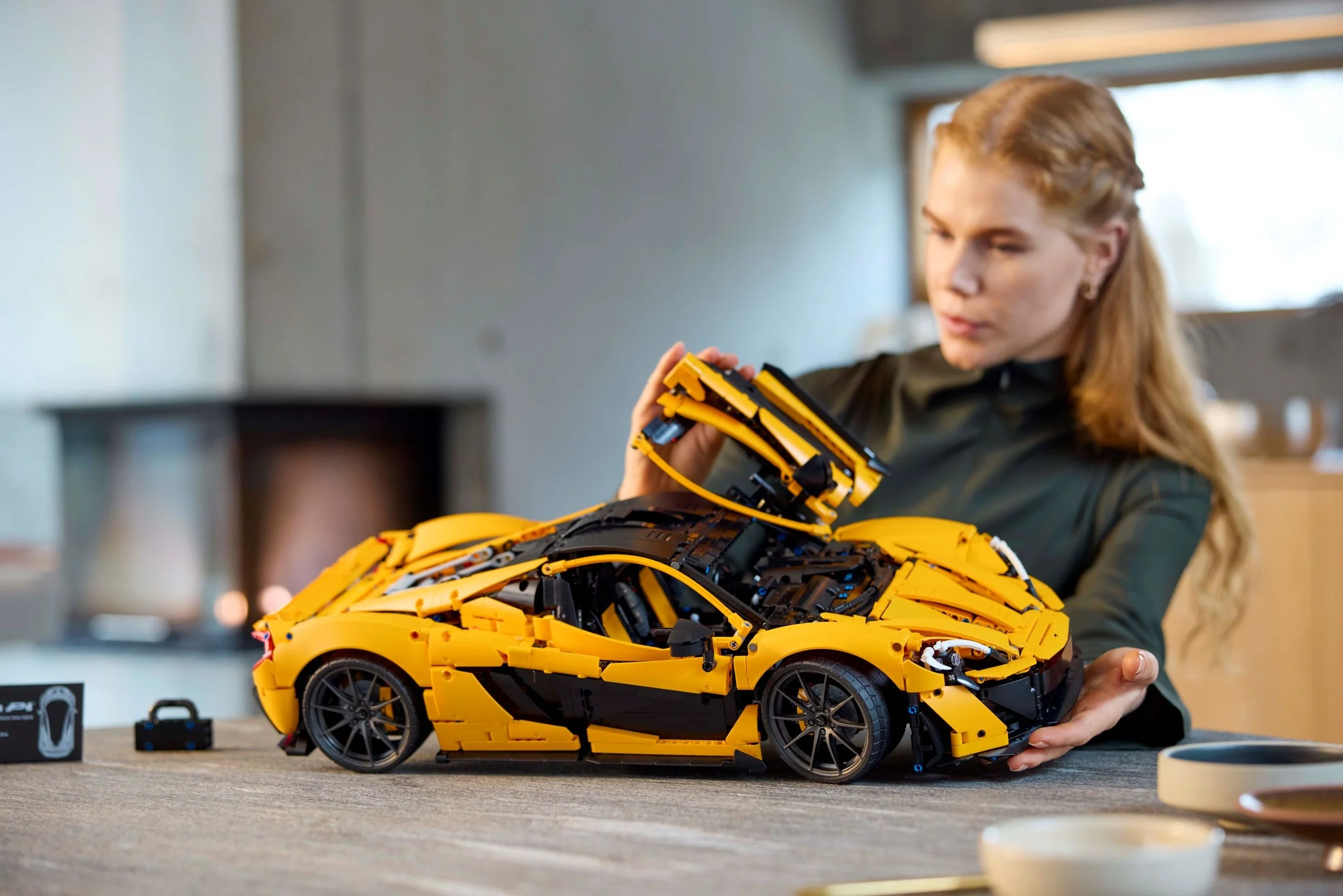 Femeie montând acoperișul galben al modelului LEGO McLaren P1. Detalii precise.