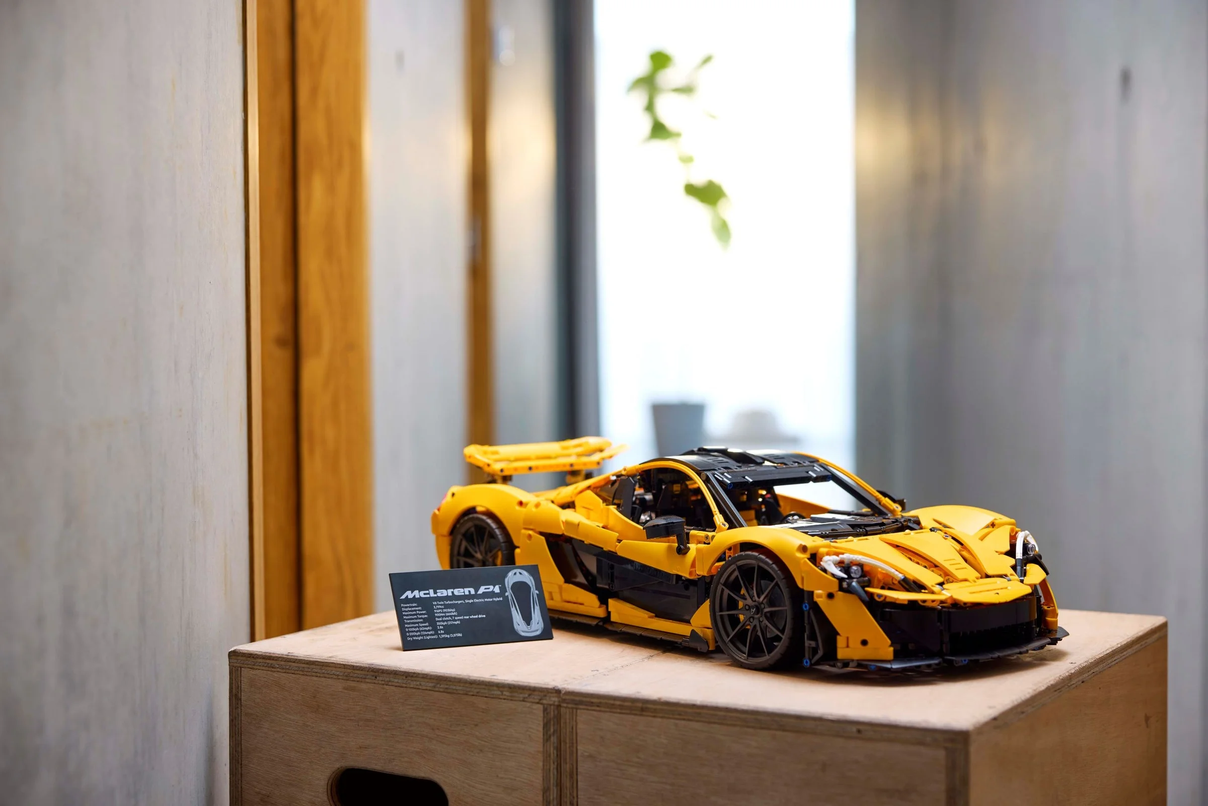 Modelul LEGO Technic McLaren P1, galben și negru, expus alături de o placă cu specificații.