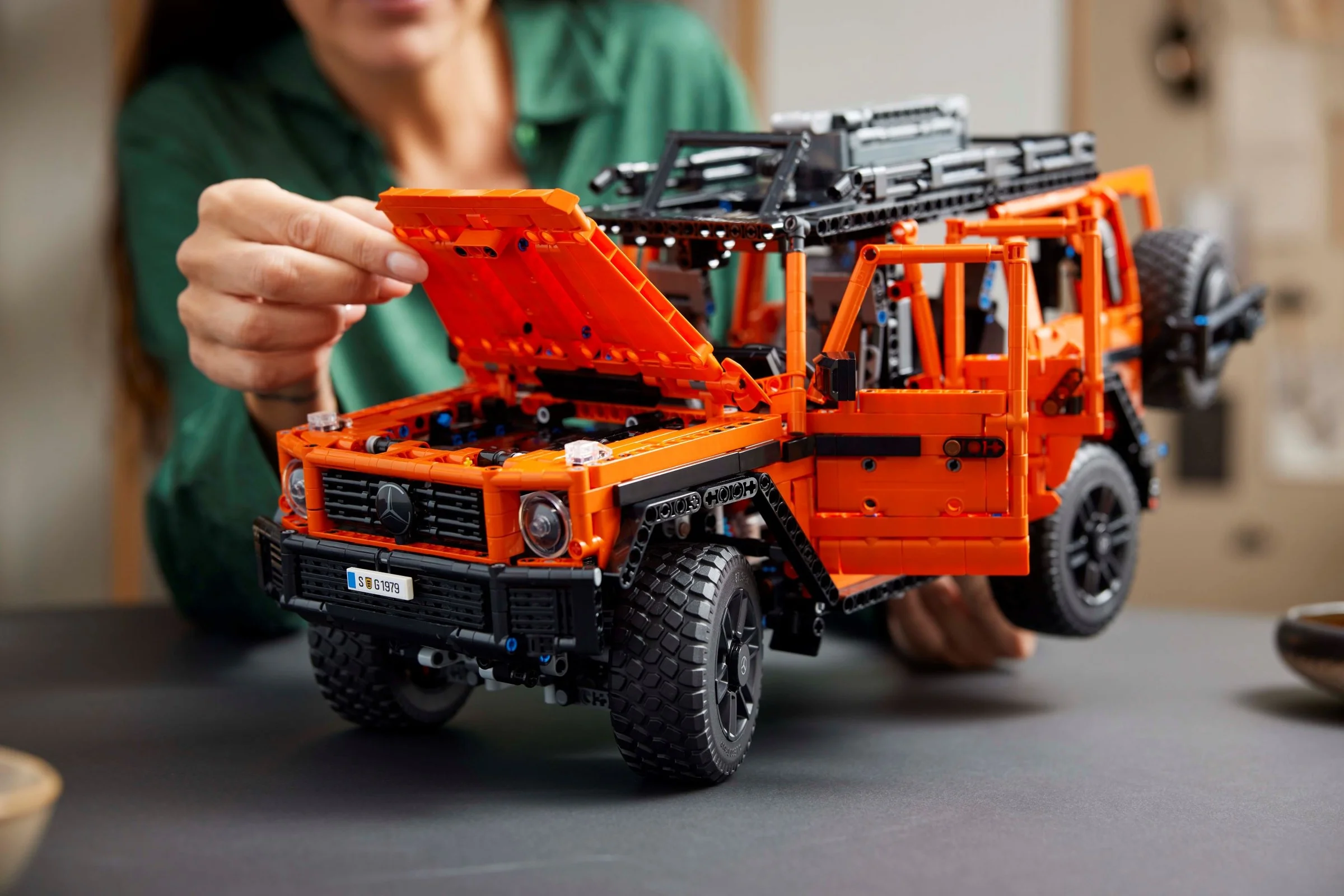Modelul Mercedes-Benz G 500 PROFESSIONAL Line cu capota ridicată și o ușă deschisă.