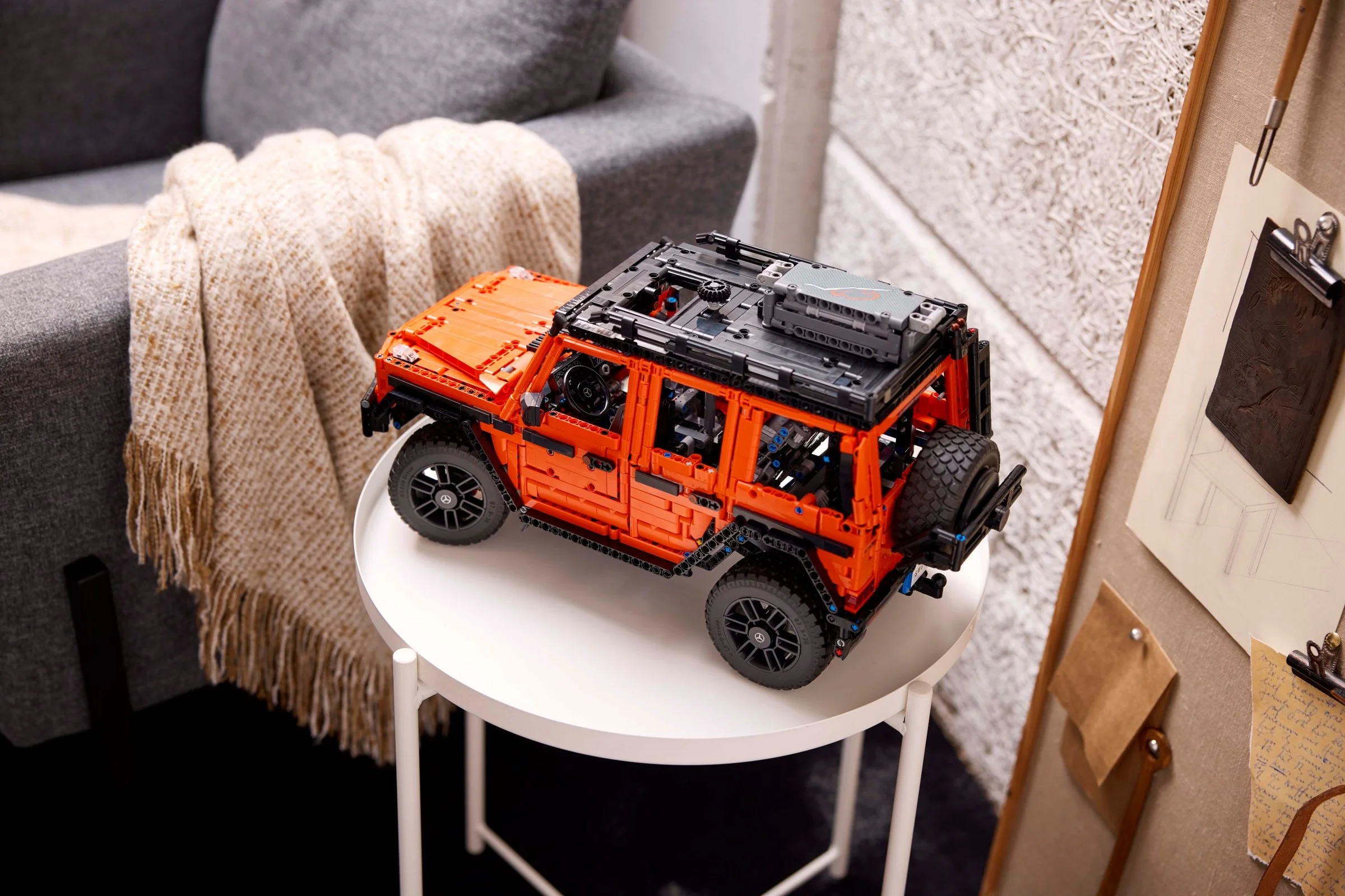 Modelul LEGO Technic Mercedes-Benz G 500, portocaliu, expus pe o măsuță albă, detaliat.