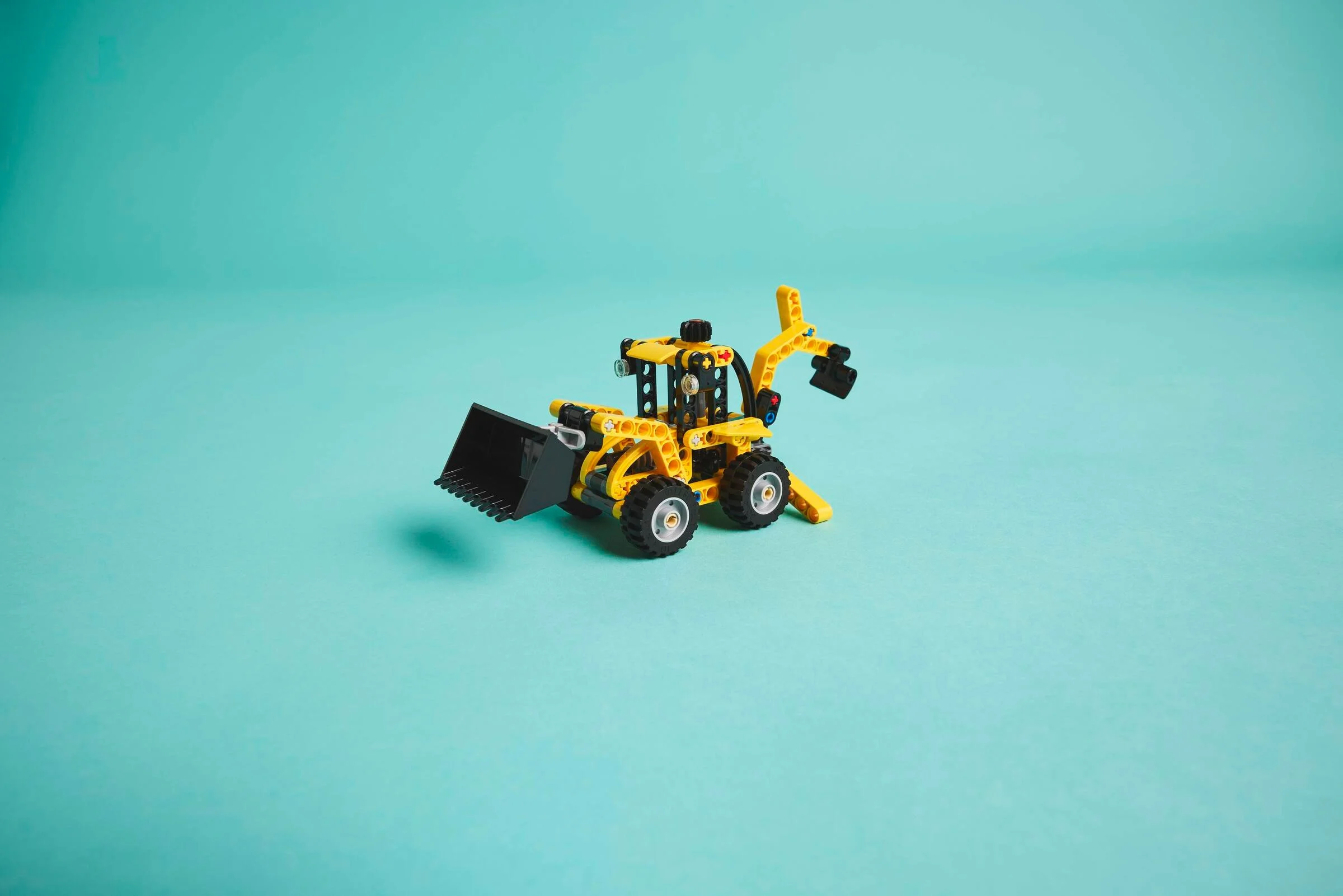 Încărcătorul LEGO Technic 42197, galben și negru, pe un fundal verde deschis.