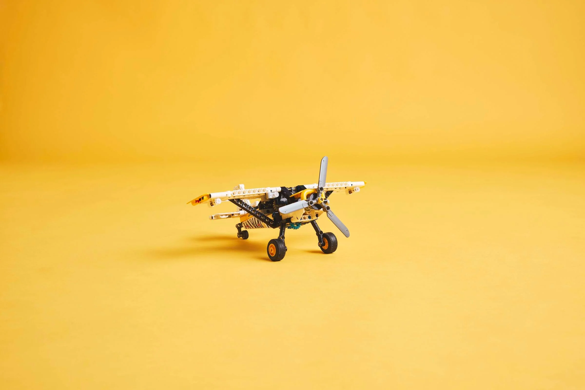 Avionul de tufiș LEGO Technic 42198, galben și negru, pe un fundal galben.