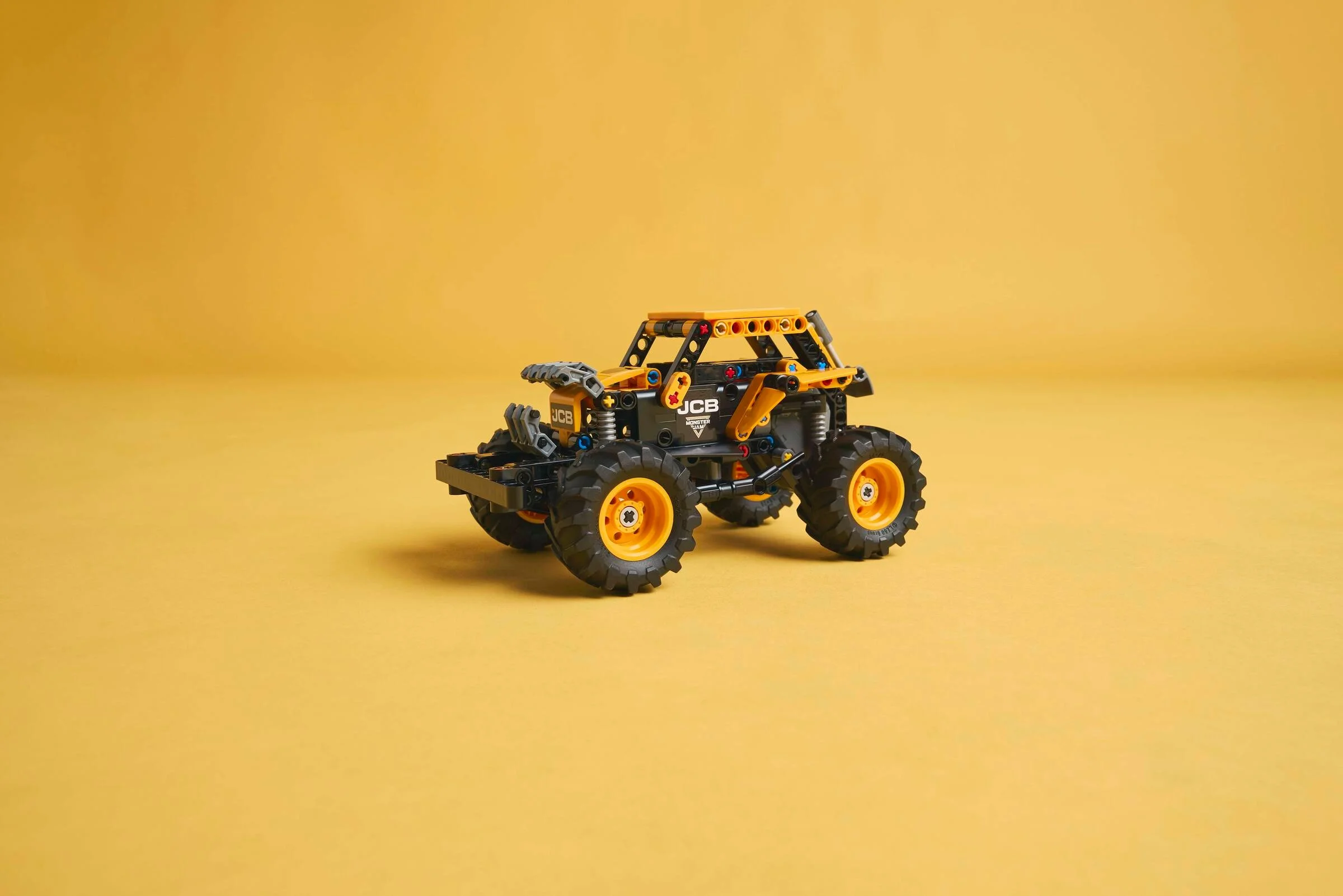 Modelul LEGO Technic Monster Jam DIGatron, galben și negru, pe un fundal galben simplu.