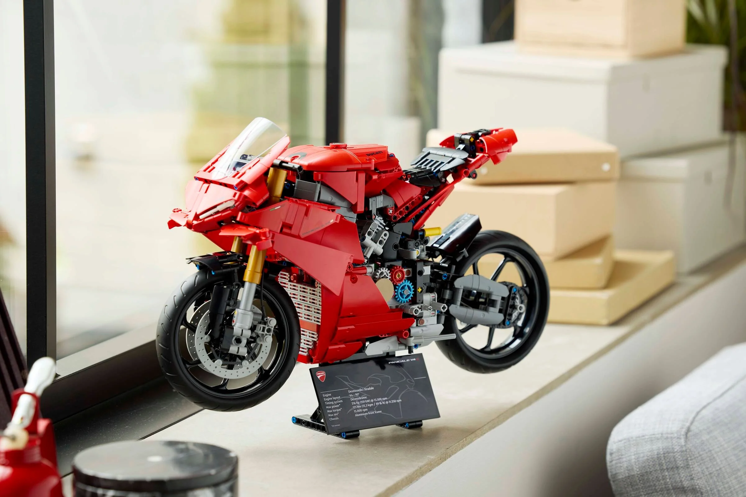 Imagine cu motocicleta LEGO Technic Ducati Panigale V4 S, expusă pe un suport elegant. Detalii precise, roșu aprins.