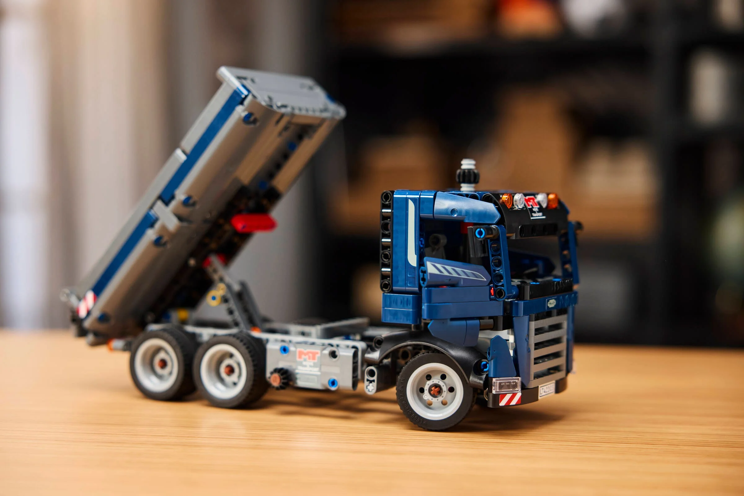 Camion basculant albastru din setul LEGO Technic 42203, cu bena ridicată.