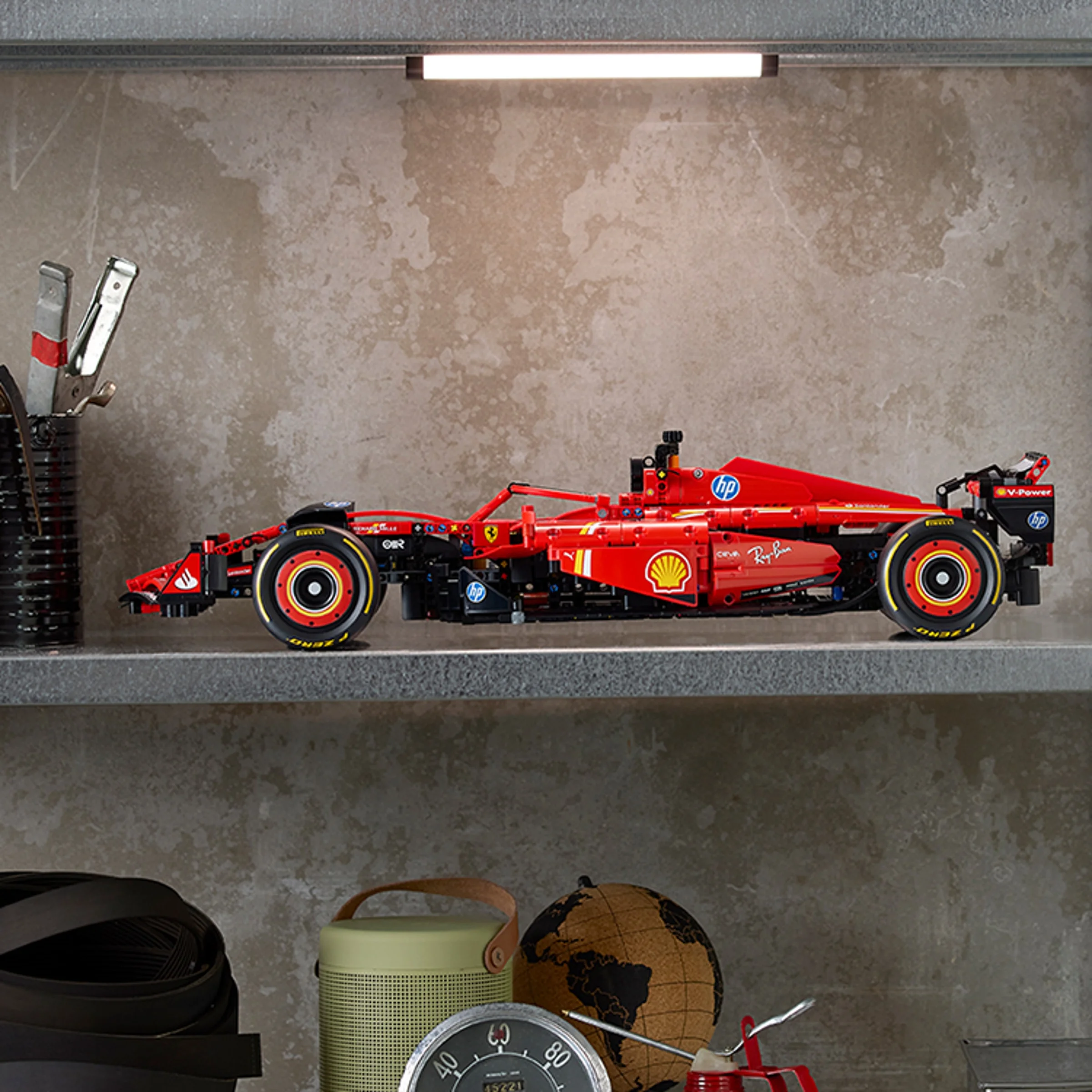 Modelul Ferrari SF-24 F1, expus pe un raft, cu detalii vizibile: roți, sigle, caroserie roșie.