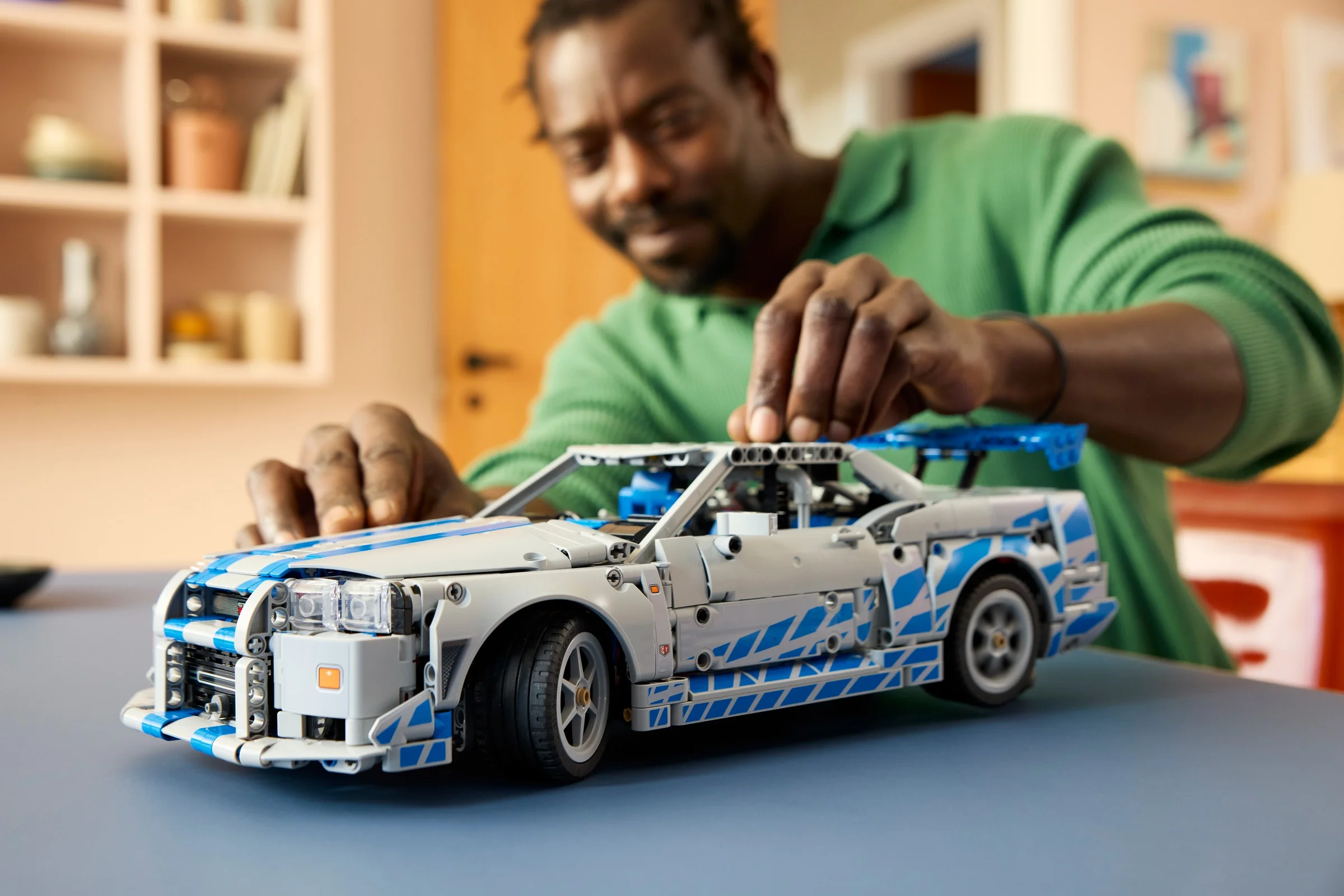 Imagine cu modelul LEGO Nissan Skyline GT-R (R34) asamblat de un adult, detaliind aspectul final.
