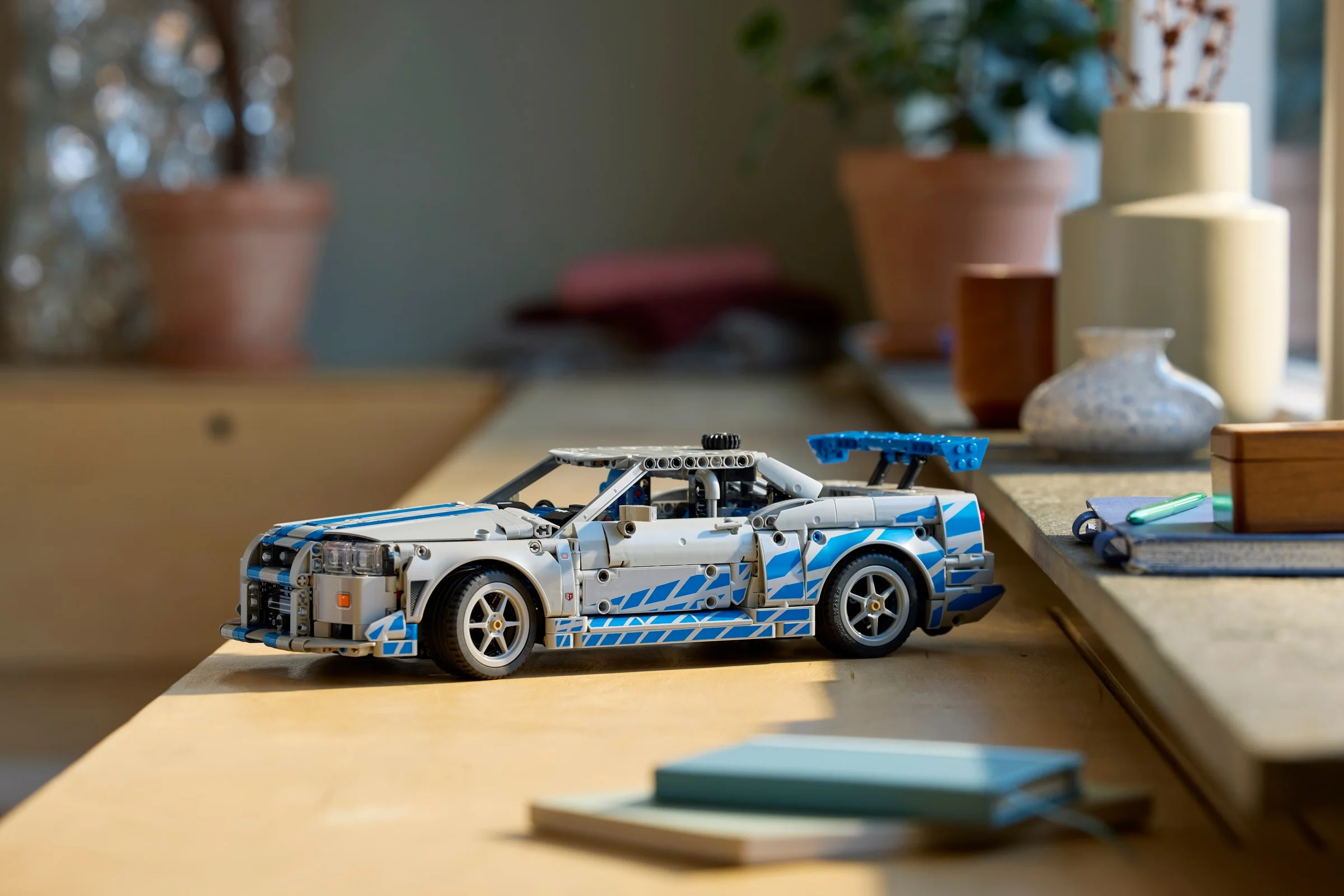 Nissan Skyline GT-R (R34) LEGO Technic, detaliat și cu dungi albastre, expus pe o suprafață lemnoasă.