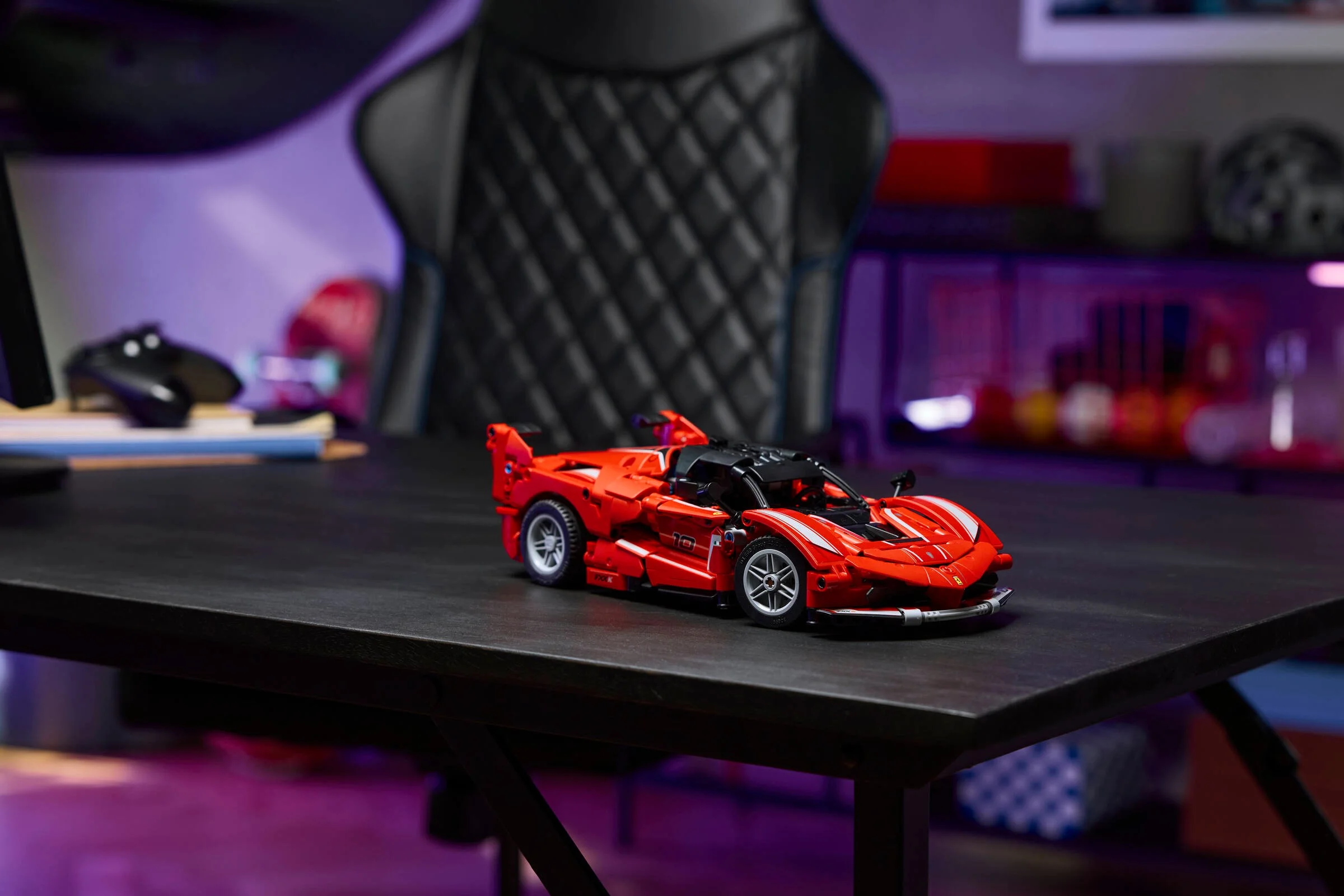 Mașină Ferrari FXX K LEGO Technic roșie pe o masă neagră, într-un cadru de gaming.