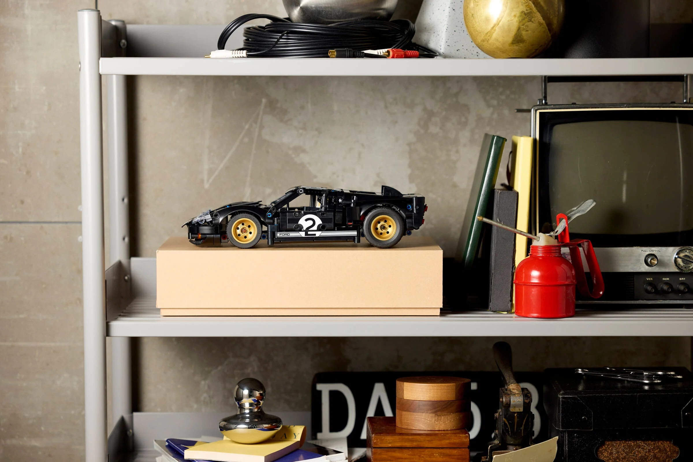 Ford GT40 MKII LEGO Technic negru pe o cutie, pe raft. Aspect realist și detaliat.