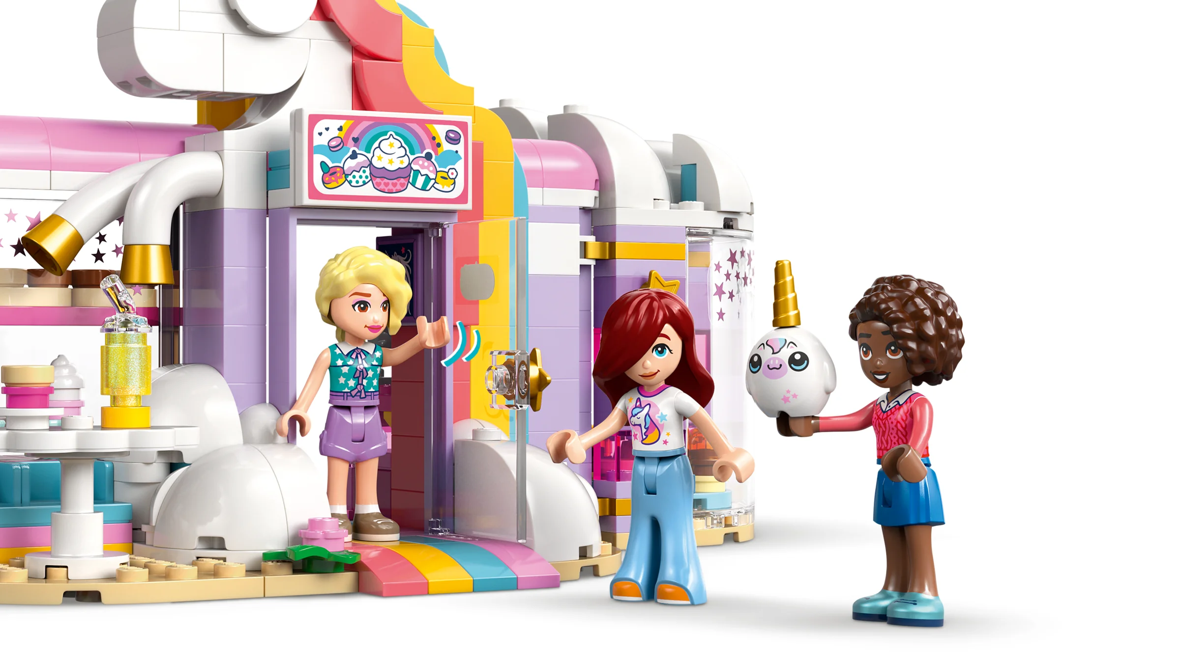 Imagine cu cafeneaua unicorn, cu trei mini-figurine Friends în fața ei.