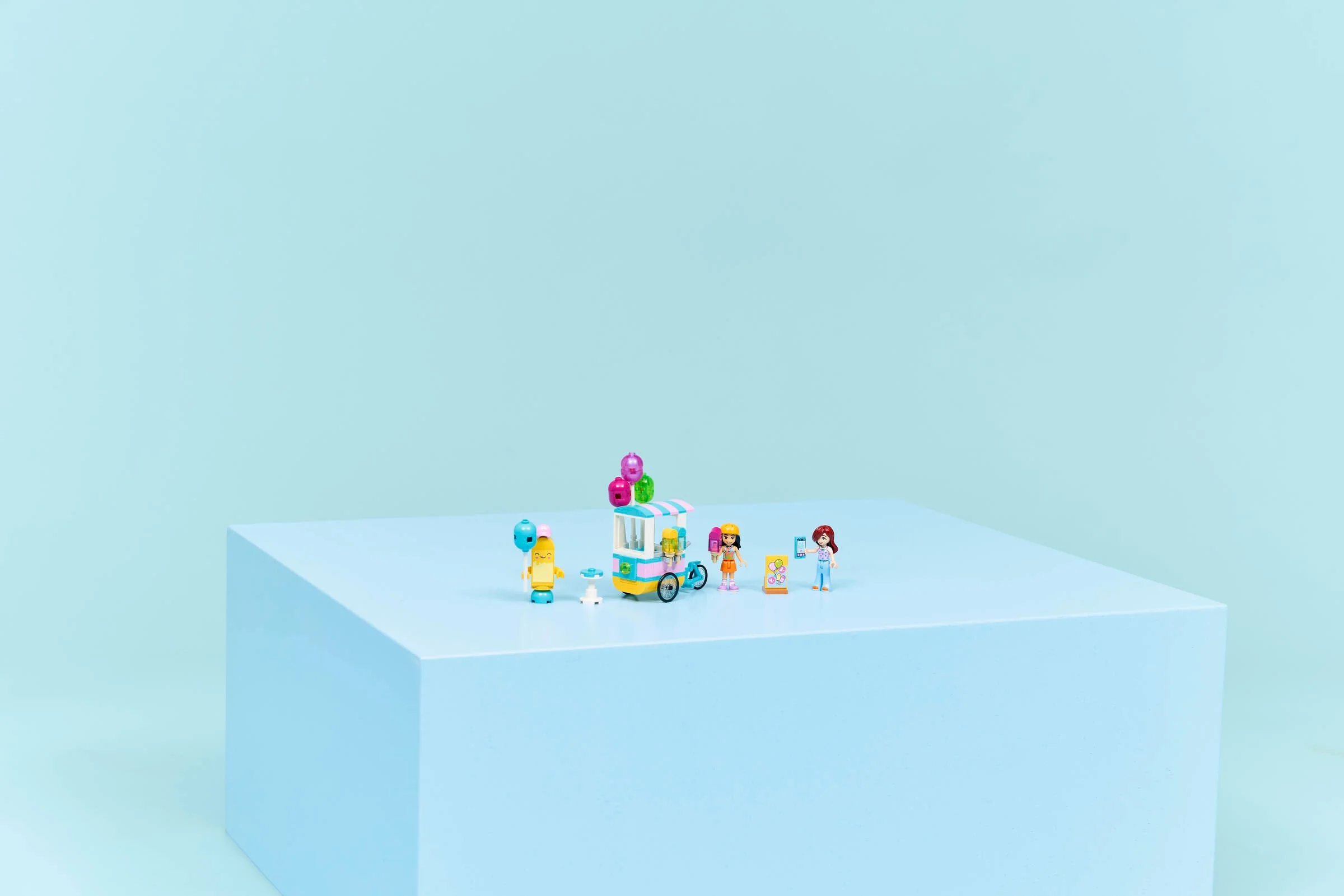 Imagine cu setul LEGO Friends 42692: Stand de înghețată și baloane, prezentând căruciorul și minifigurinele.