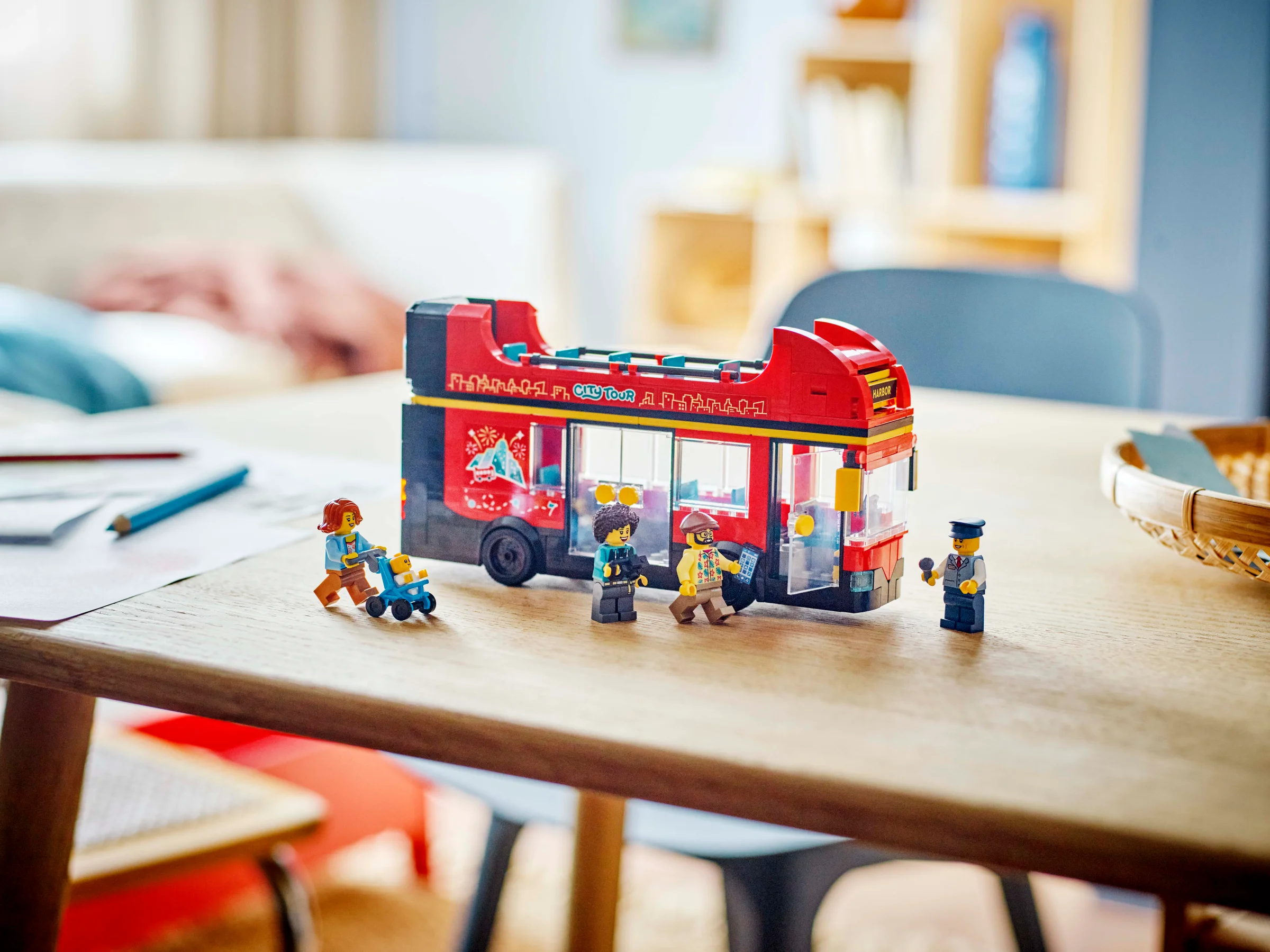 Autobuzul supraetajat de turism LEGO City și minifigurinele incluse sunt prezentate pe o masă.