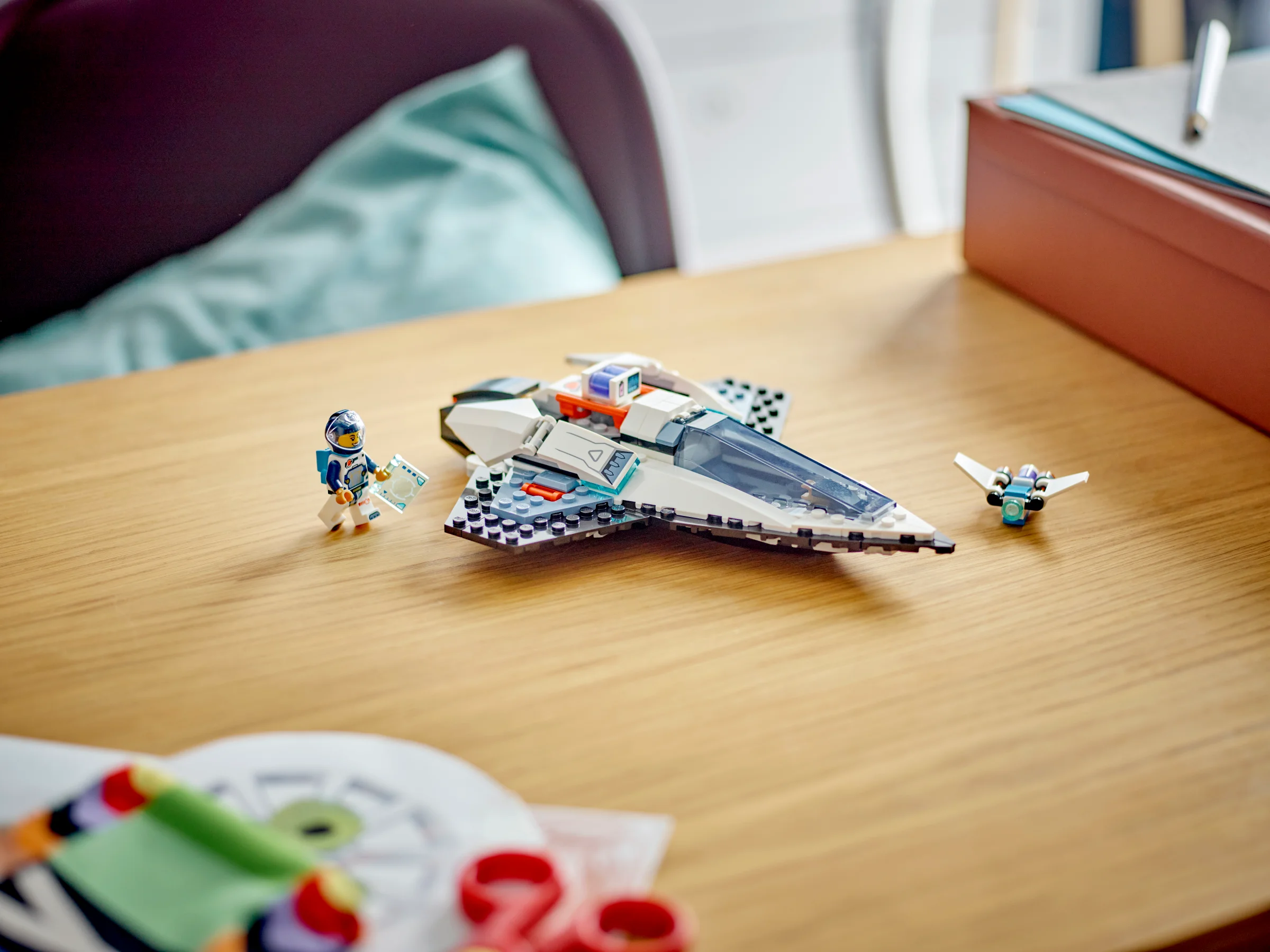 O imagine cu nava spațială LEGO 60430 și o minifigurină astronaut pe o masă.