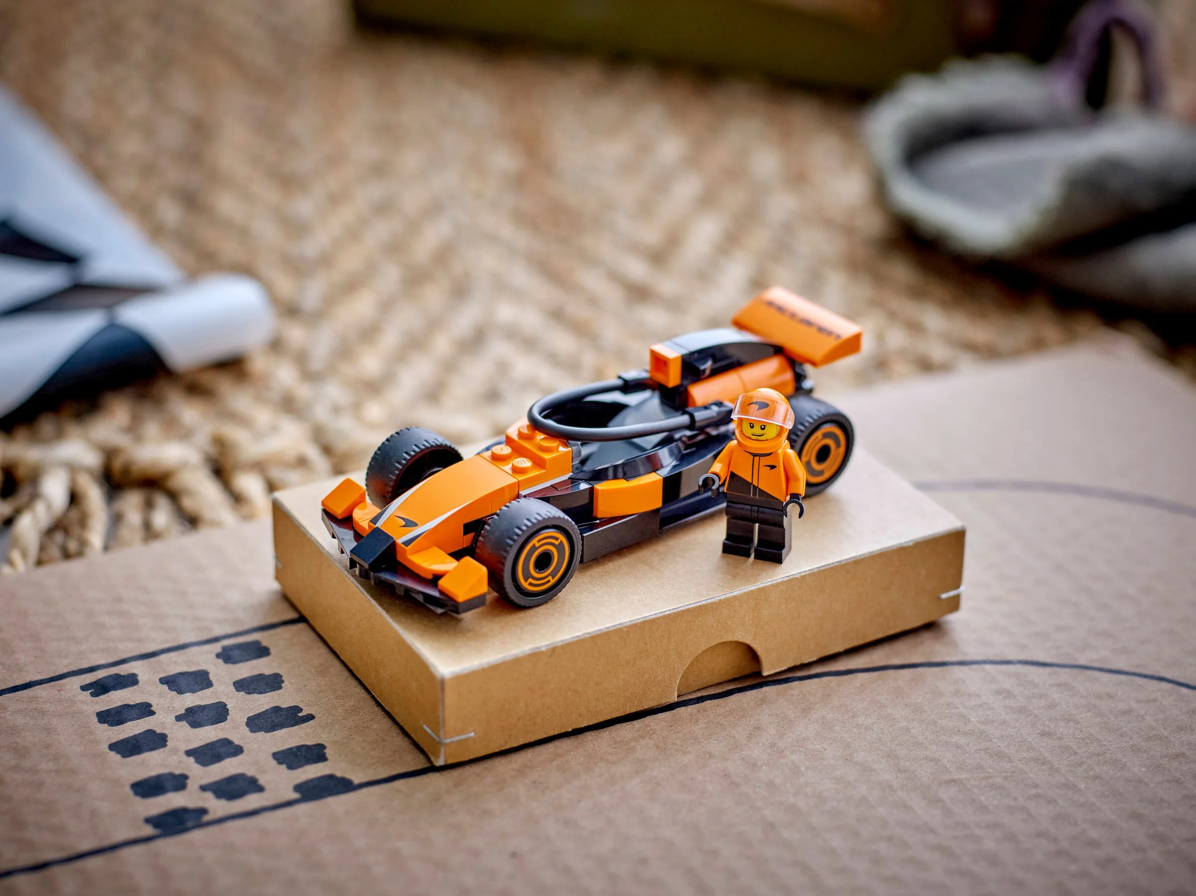 Modelul LEGO McLaren F1 și minifigurina șoferului, prezentate pe un fundal creativ.