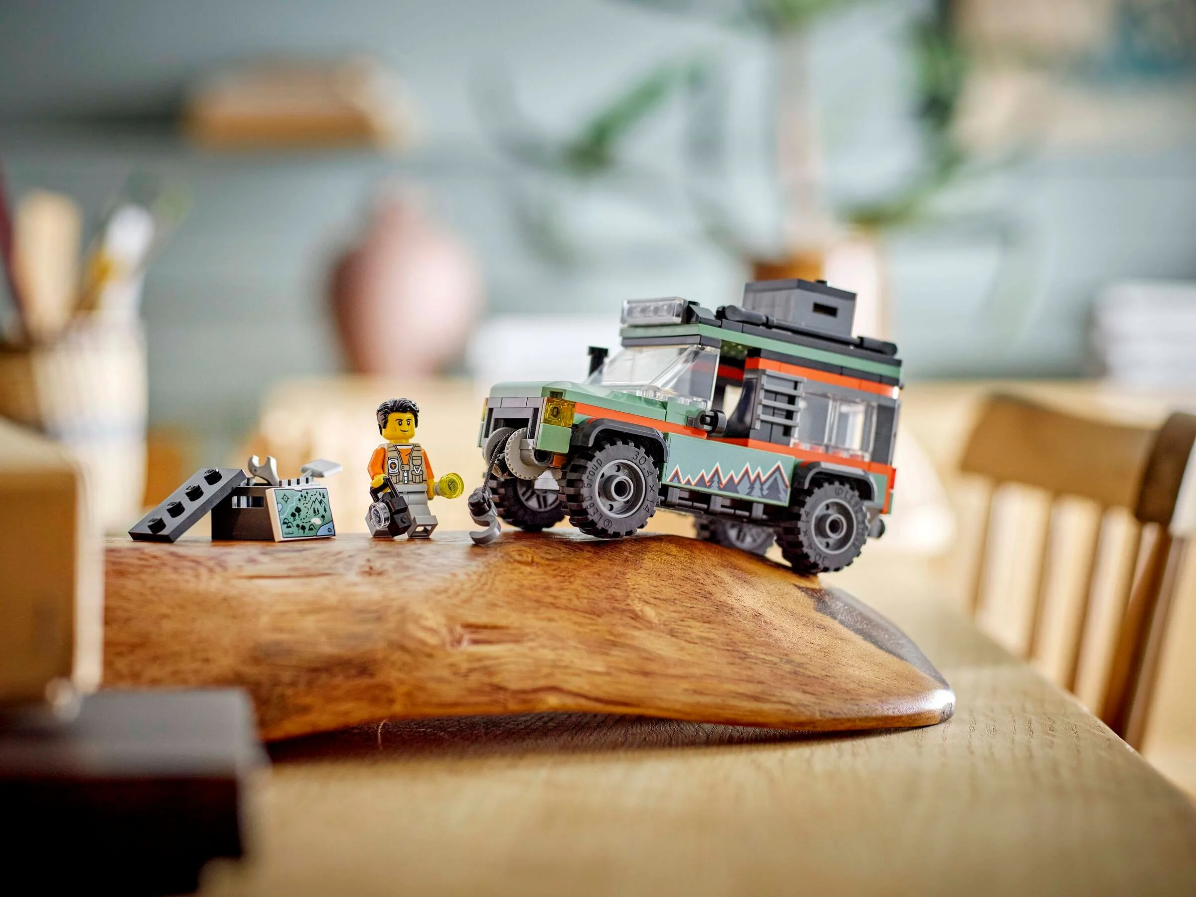 Camionul de munte off-road LEGO 60447, cu o minifigurină și accesorii pe o suprafață de lemn.
