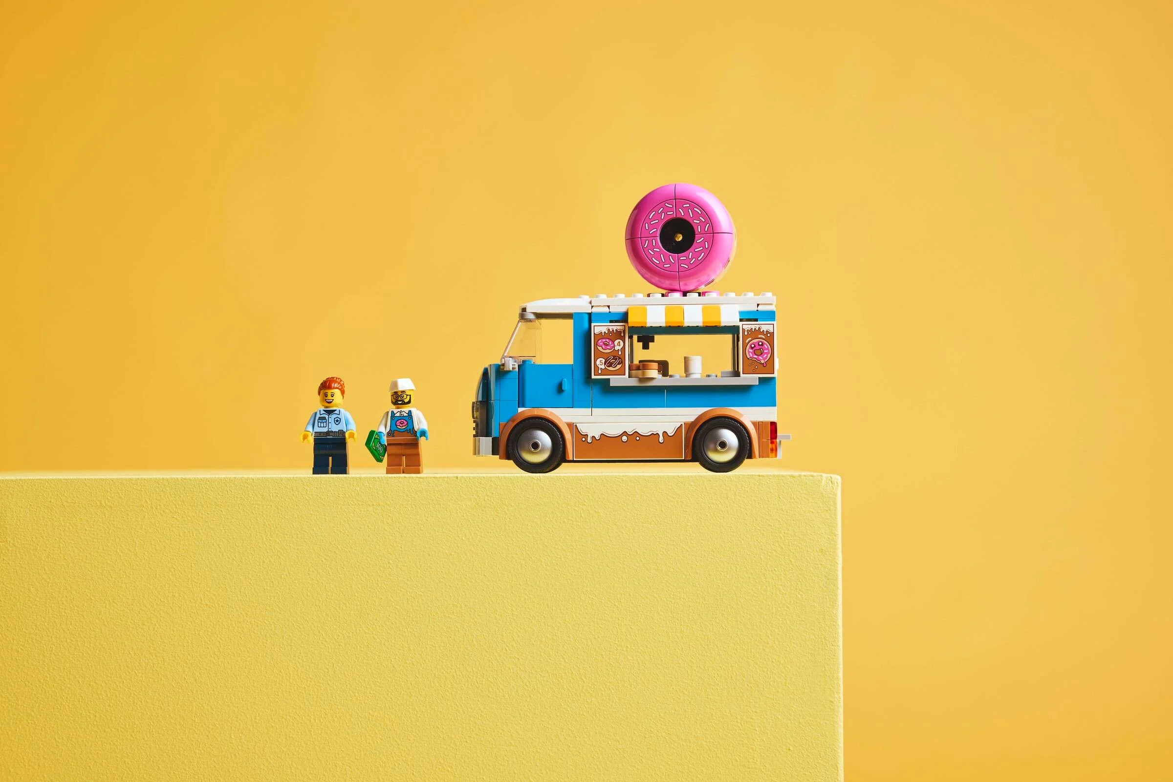 Camionul cu gogoși LEGO City 60452, prezentând două minifigurine și detaliile modelului.