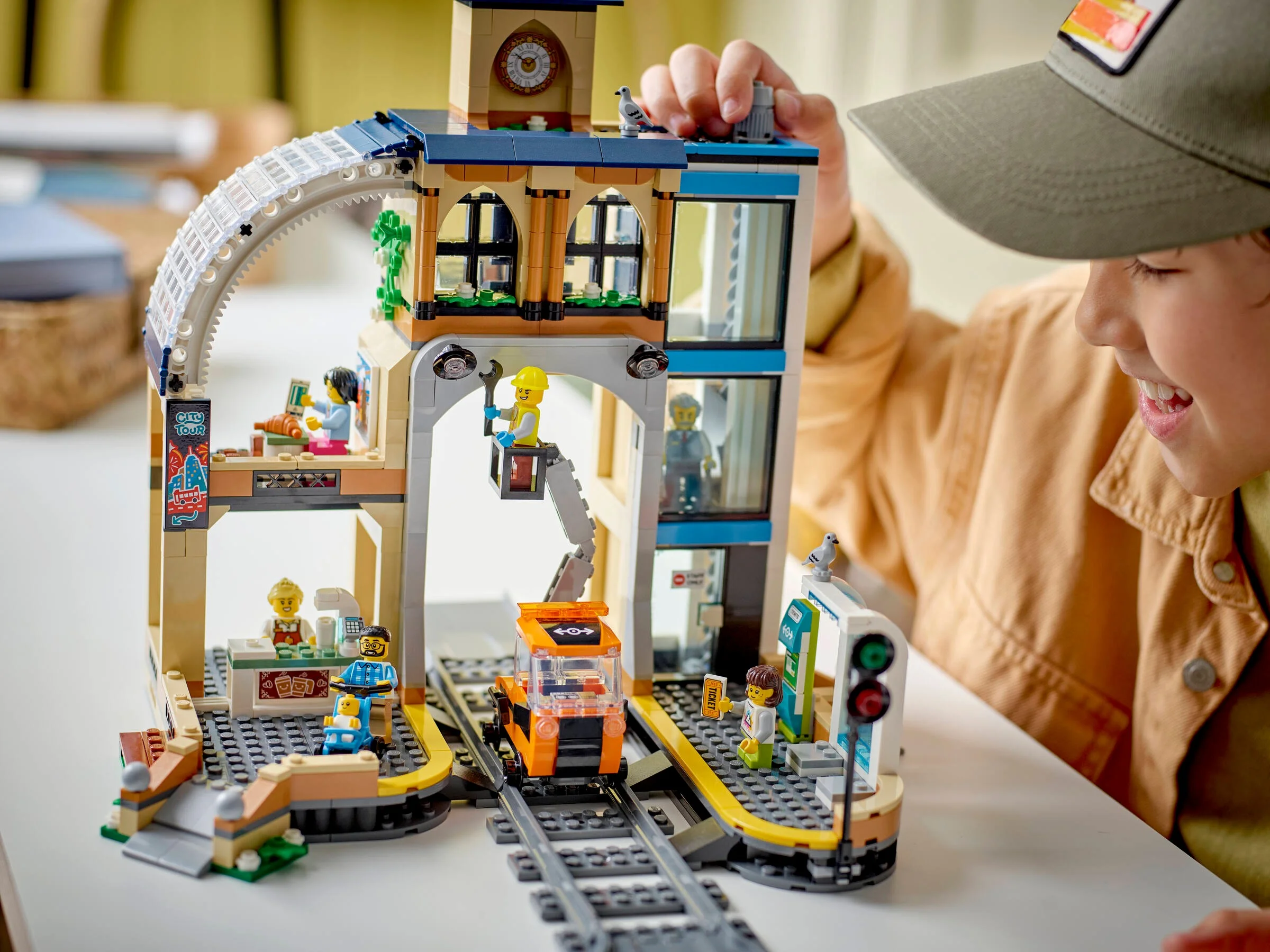 O imagine cu setul LEGO 60469, Gara Centrală, arătând diverse zone și minifigurine.
