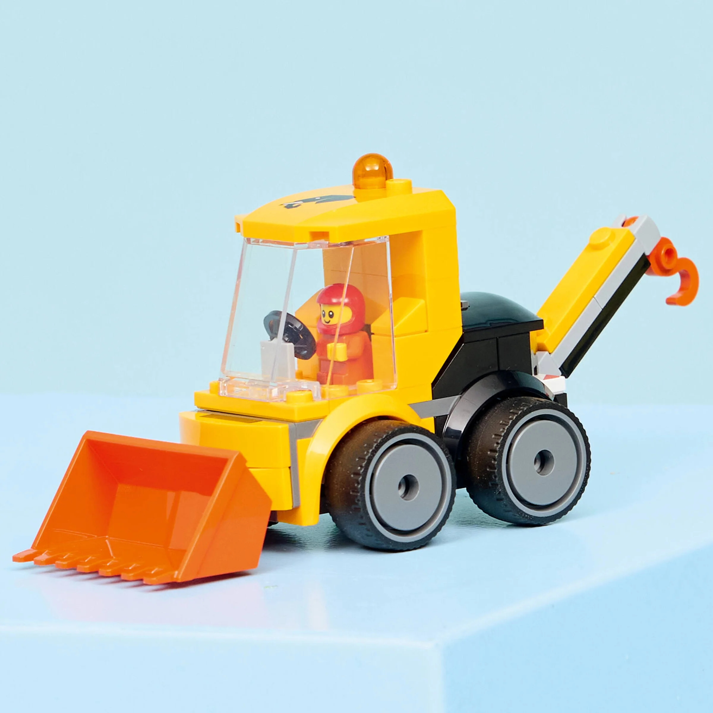 Imagine cu excavatorul galben LEGO 60483, cu cupă portocalie și minifigurină în interior.