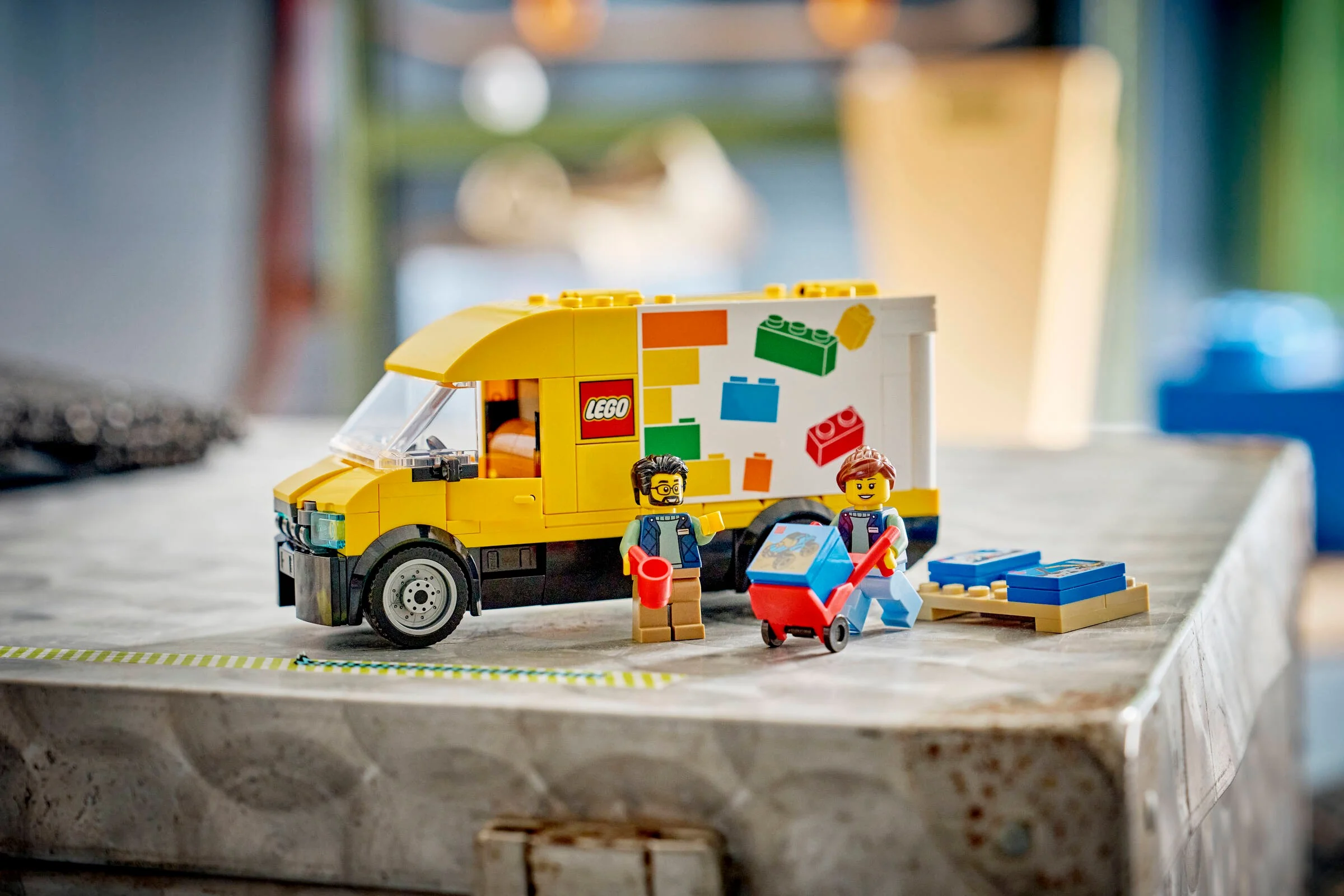 Camionul LEGO galben cu decorațiuni și două minifigurine care descarcă piese LEGO.