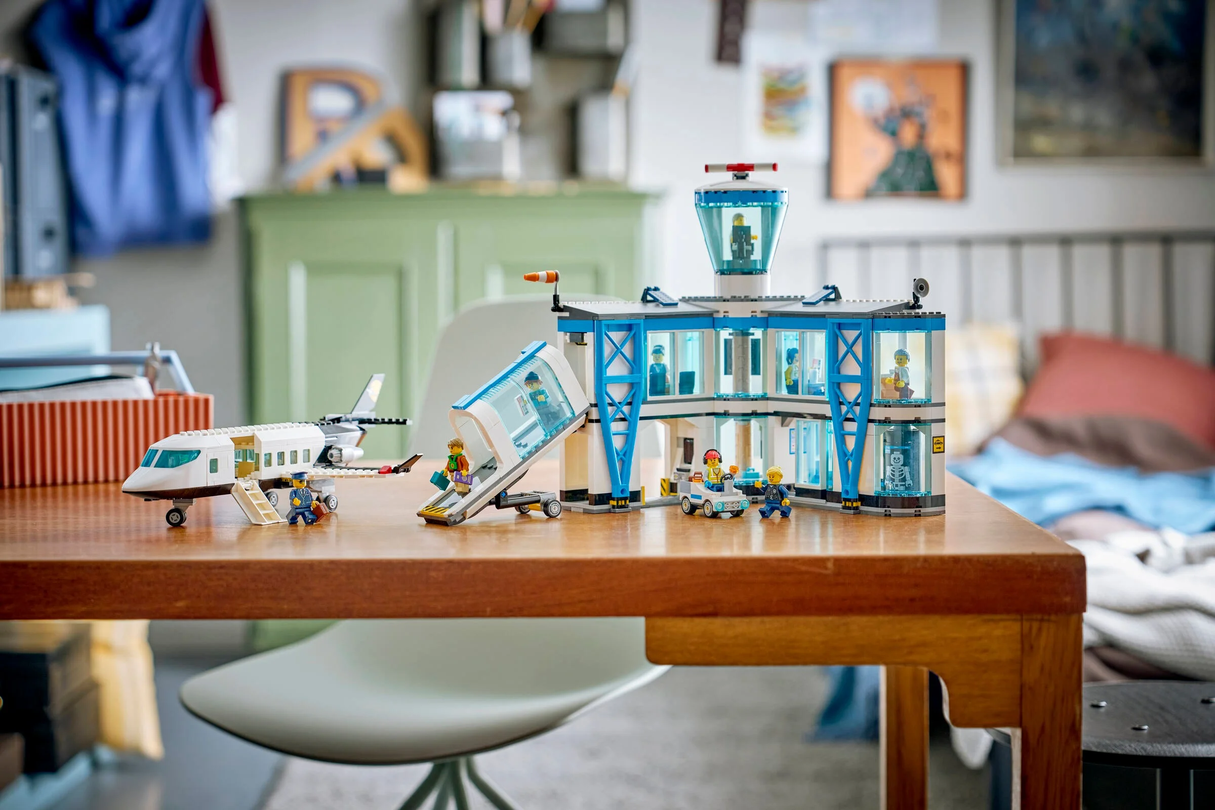 Imagine cu Aeroportul LEGO 60502, avion și minifigurine pe masă. Atmosferă prietenoasă.