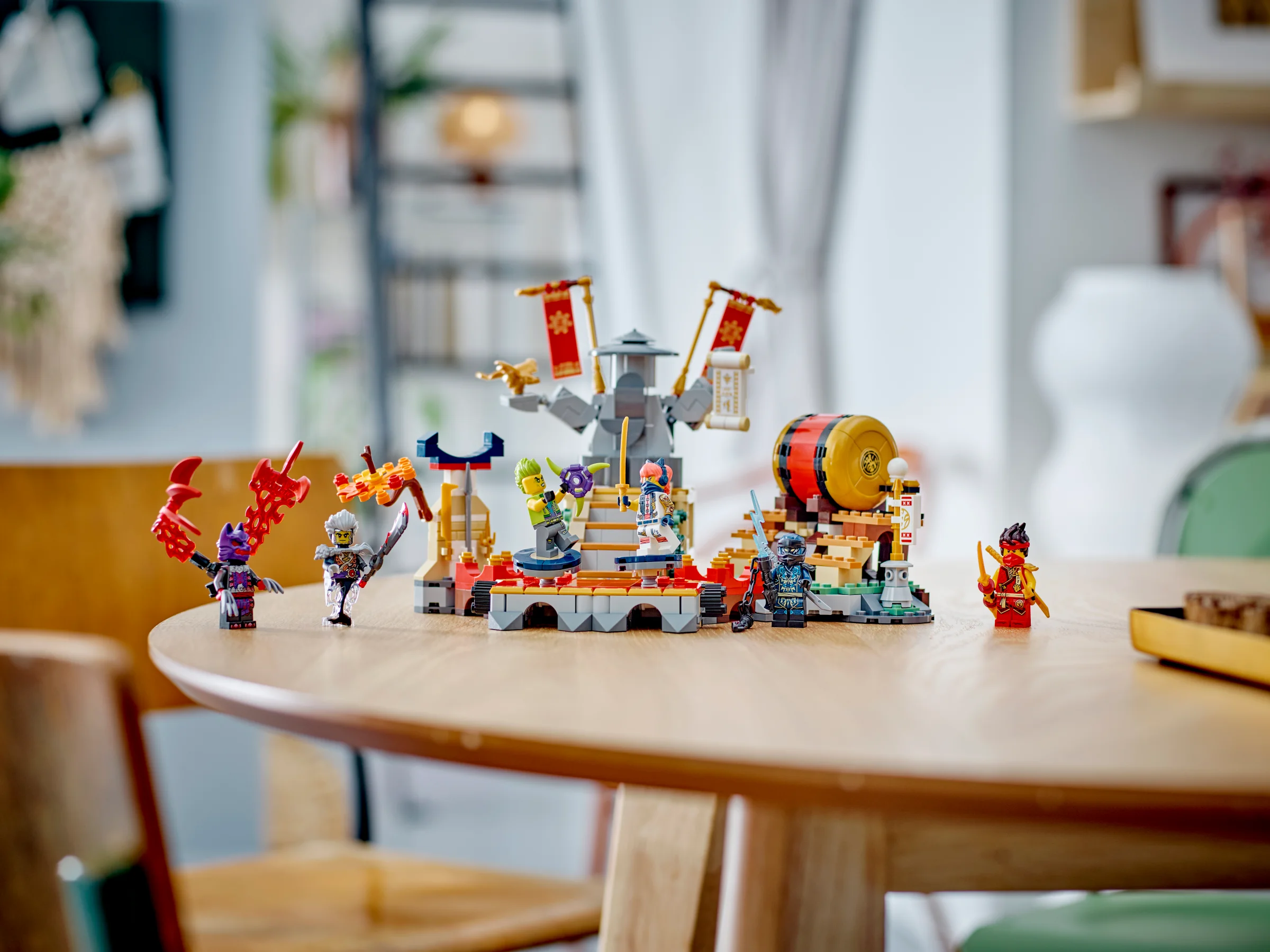 Arena de luptă Ninjago, cu minifigurine și elemente de decor pe o masă din lemn.