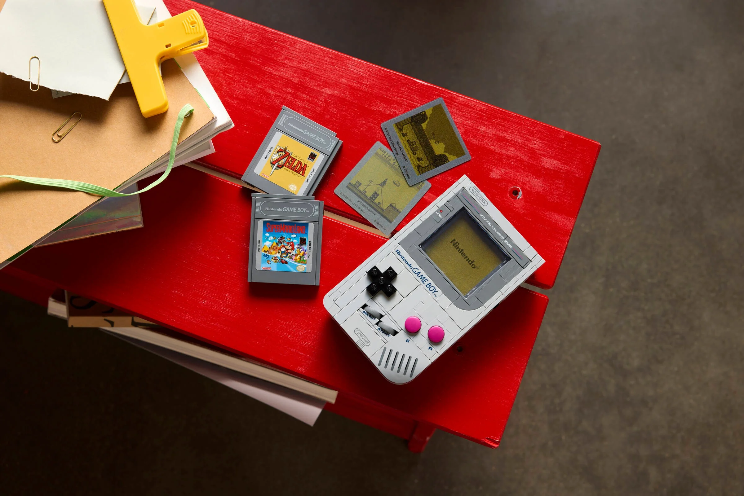 O vedere de sus a LEGO Game Boy și a cartușelor de joc, pe o masă roșie.